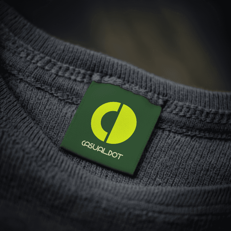 Close-up of a t-shirt label with the Casual Dot logo, showcasing a stylized "C" and "D" in a green square.