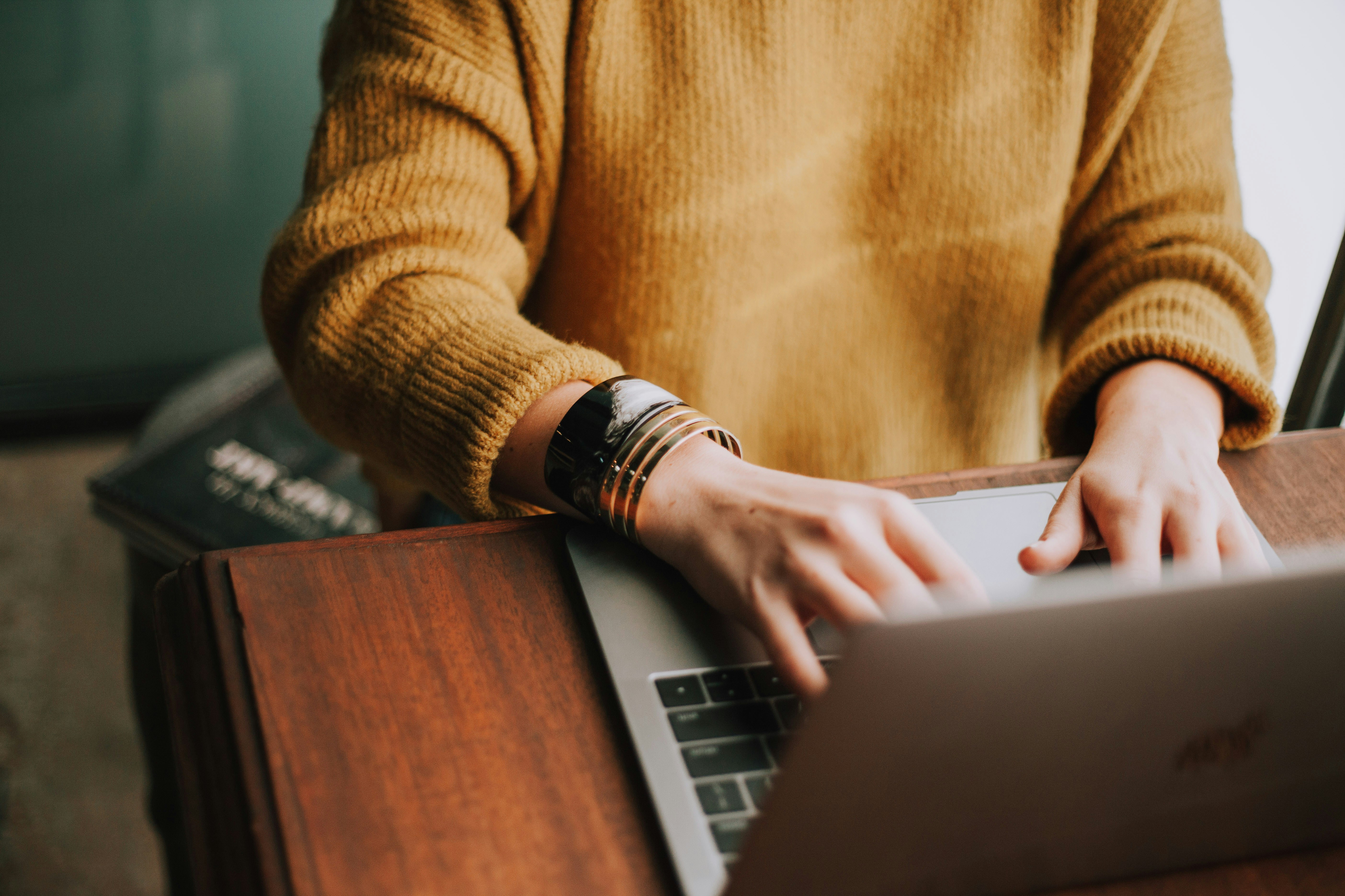 A woman sitting at a desk, focused on typing on her laptop.