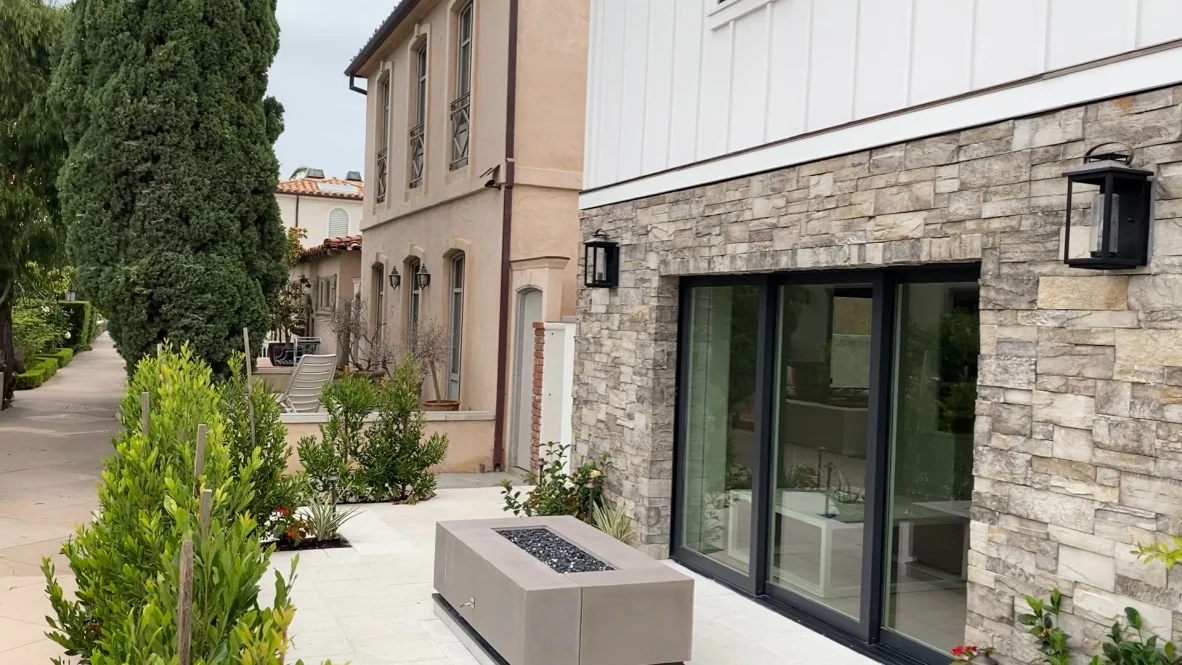 Paved residential patio with a fire table beside sliding doors.