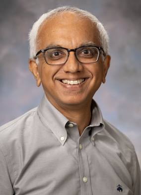 Smiling middle aged man with white hair, wearing a formal shirt