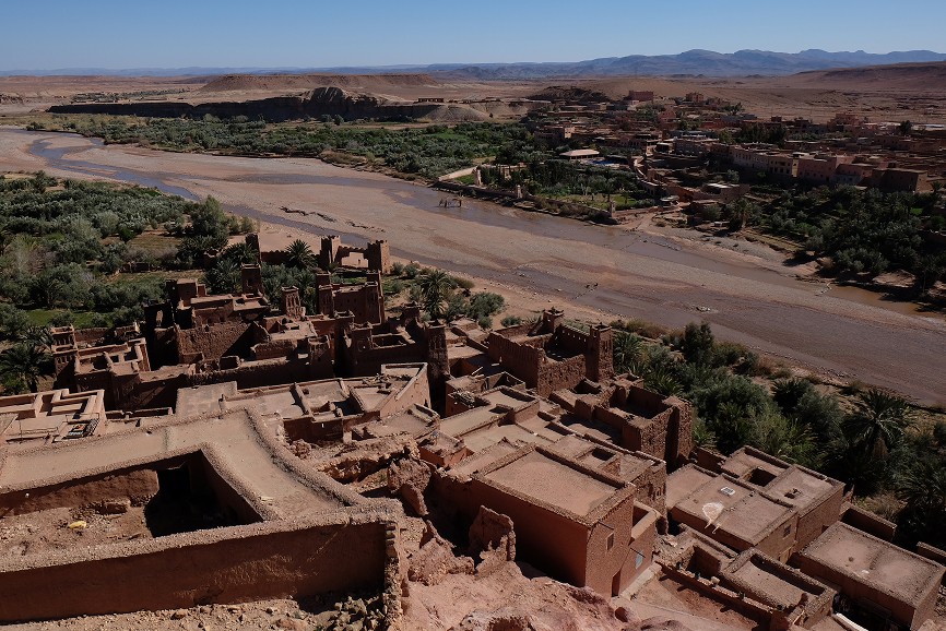 A smiling graduate in cap and gown holds hands up.