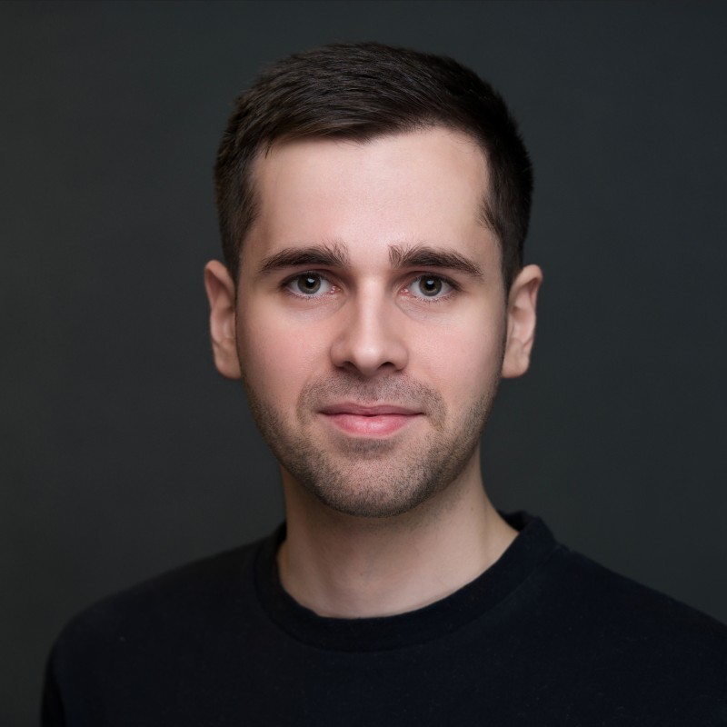 Studio portrait of Vlad Matsiiako against a slate gray backdrop, illuminated by soft lighting.