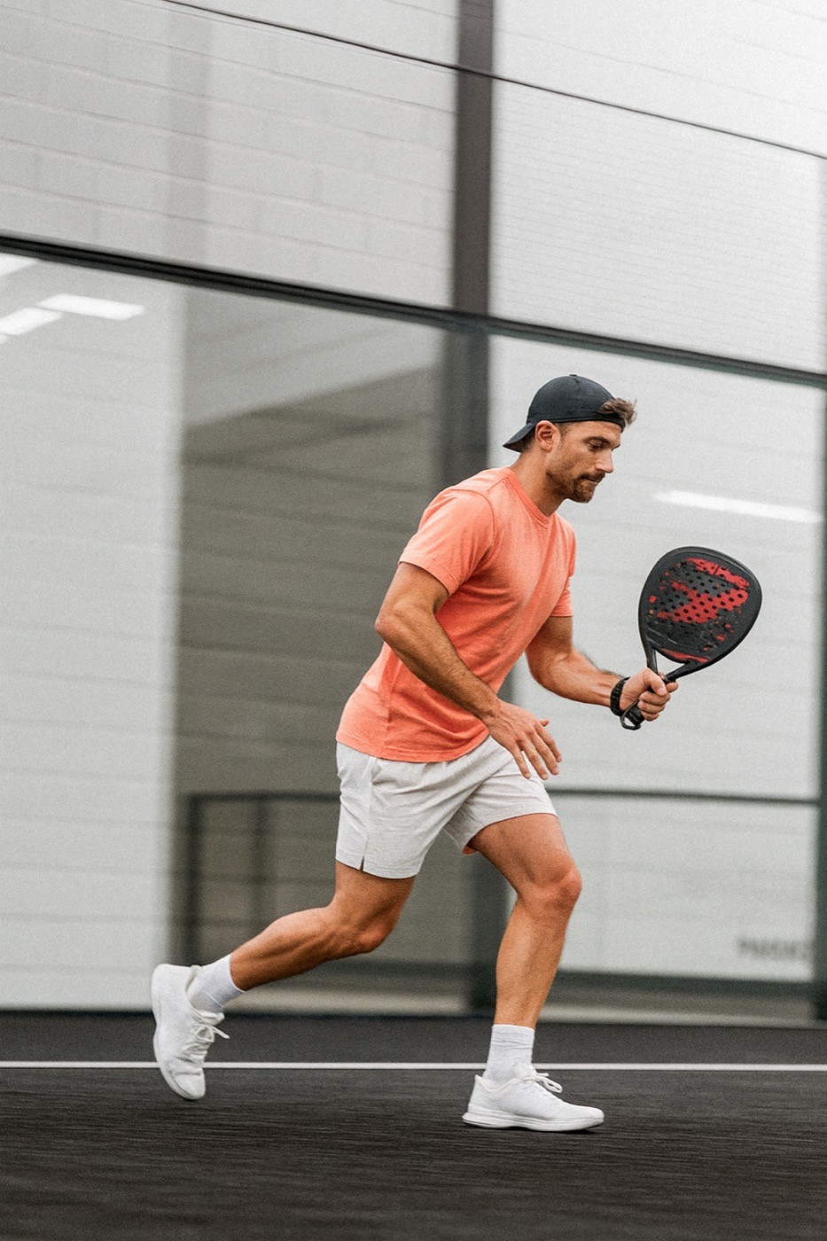Padelspieler in Bewegung auf dem schwarzen Court, konzentriert auf den nächsten Schlag – Dynamik und Spielfreude im Stil von Padelnero.