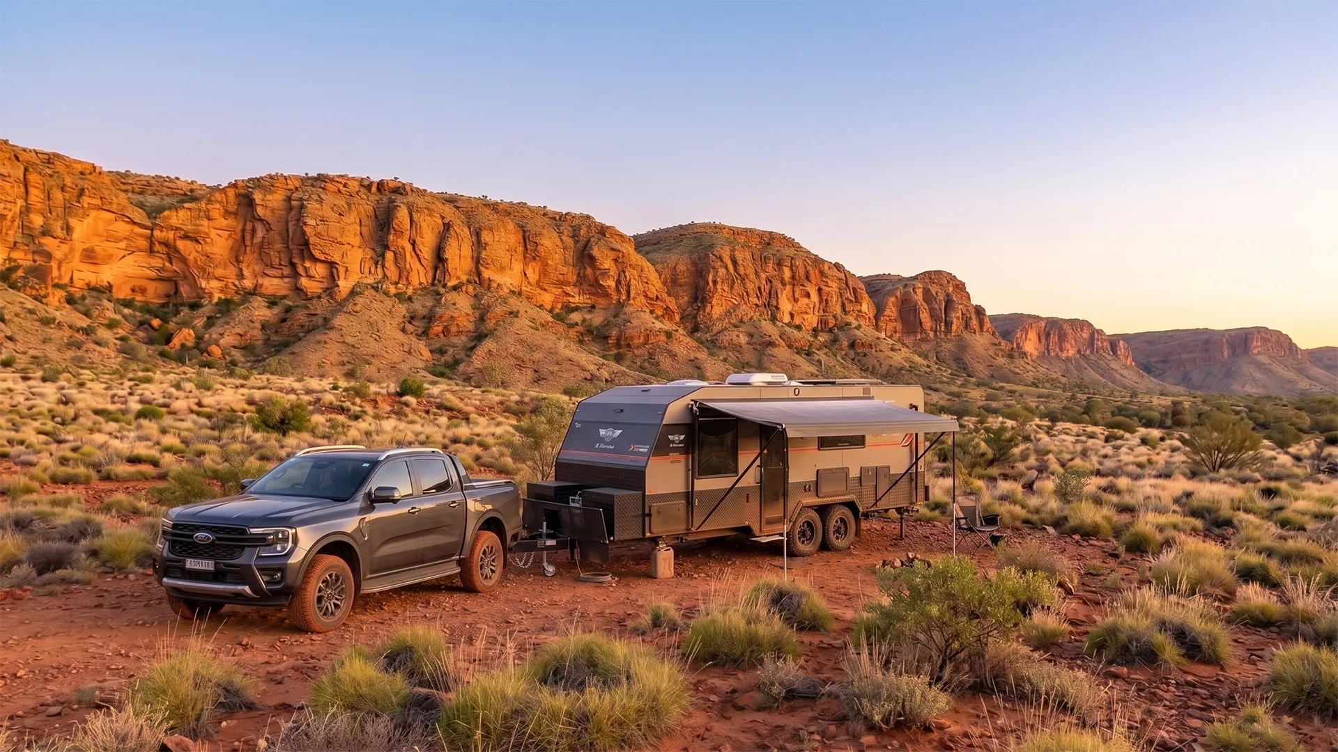 Australian made off road caravan parked at a remote camp at first light, red dirt and ochre gorges in the background, awning out