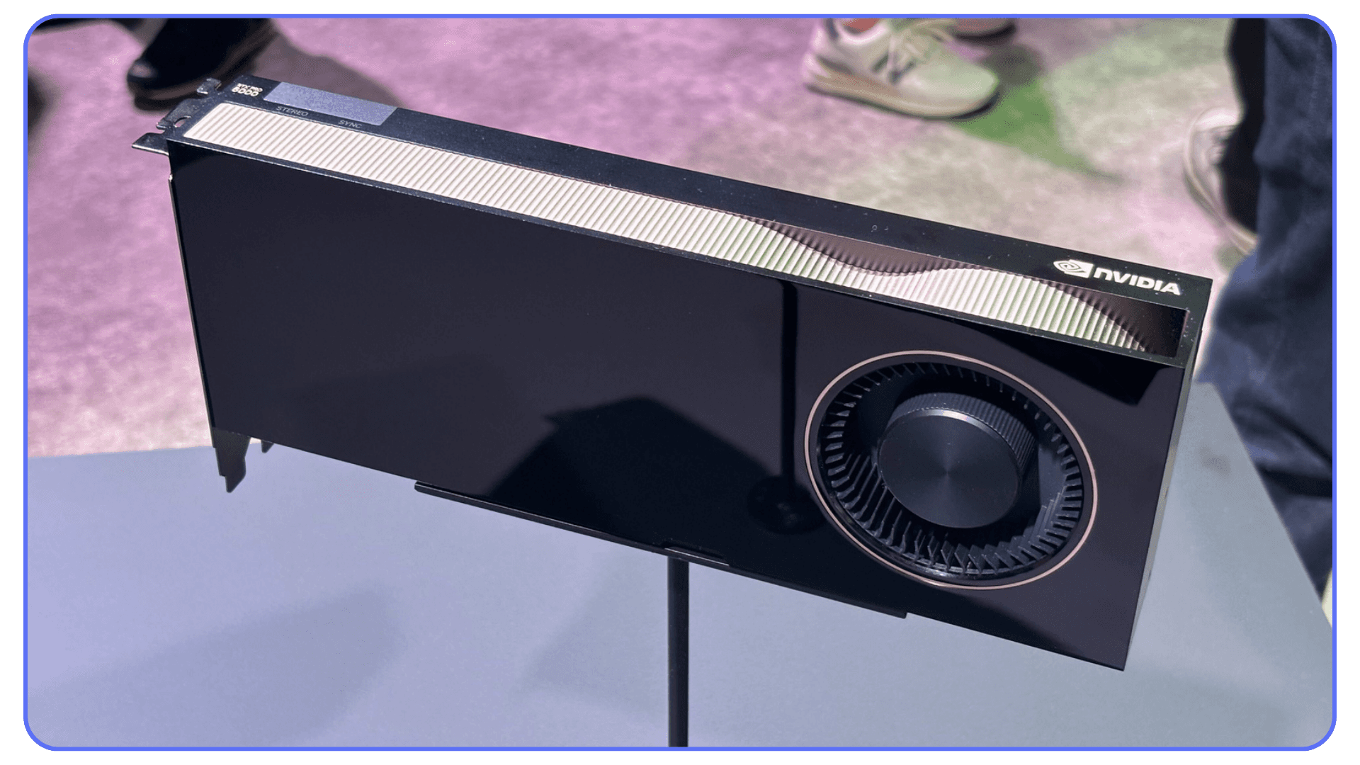 NVIDIA professional GPU on display stand at an event, with compact black casing and circular cooling fan design.