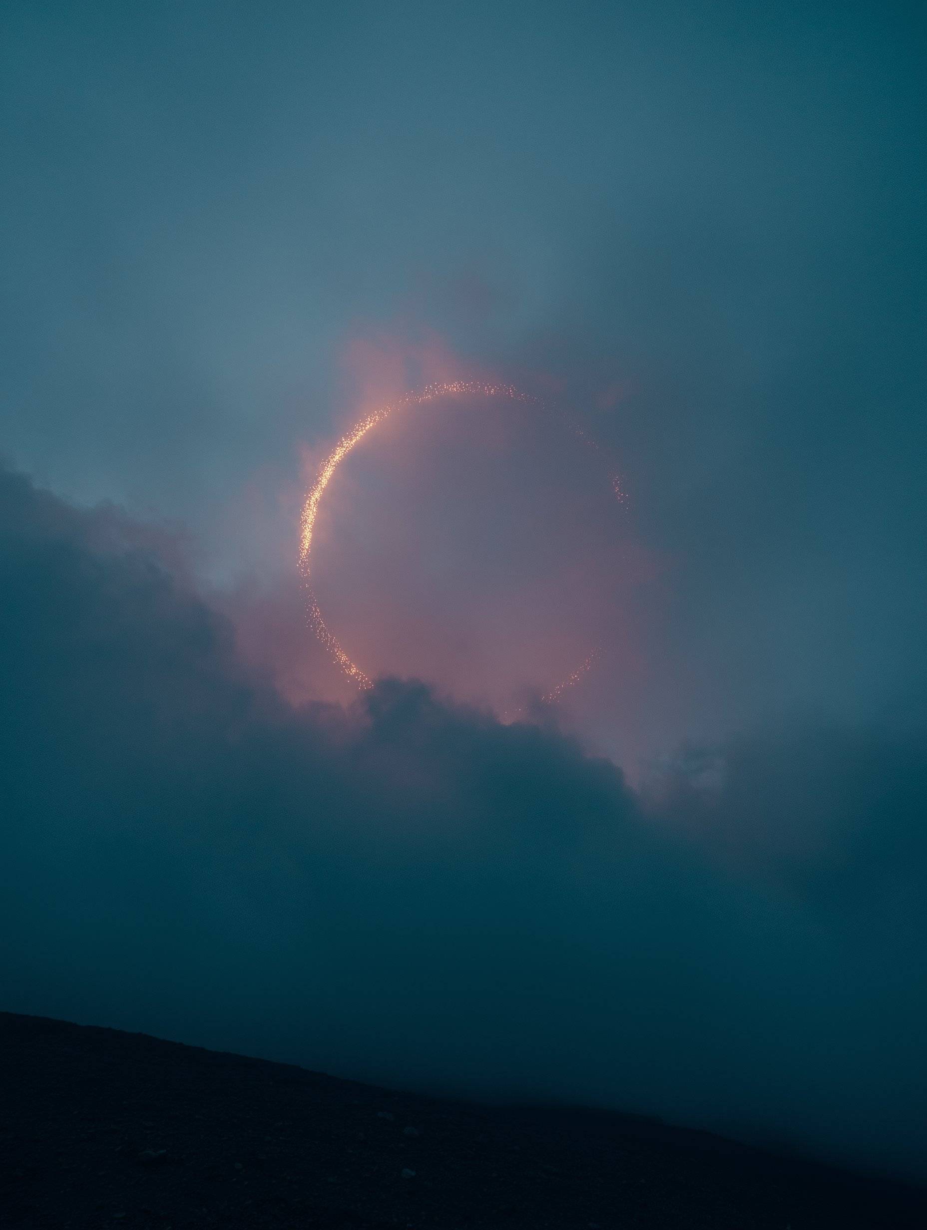 Glowing circular light orb in turquoise night sky