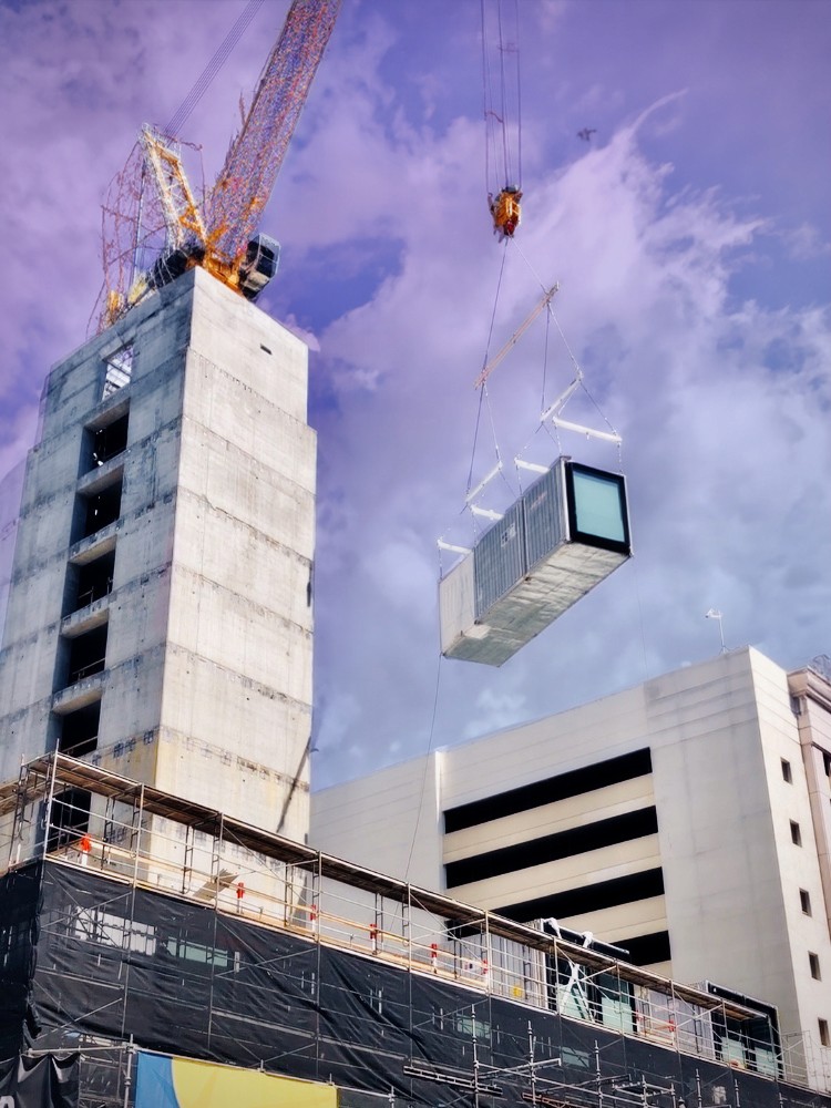 A crane hoists a modular unit at citizenM DTLA, exemplifying cutting-edge urban design in Los Angeles.