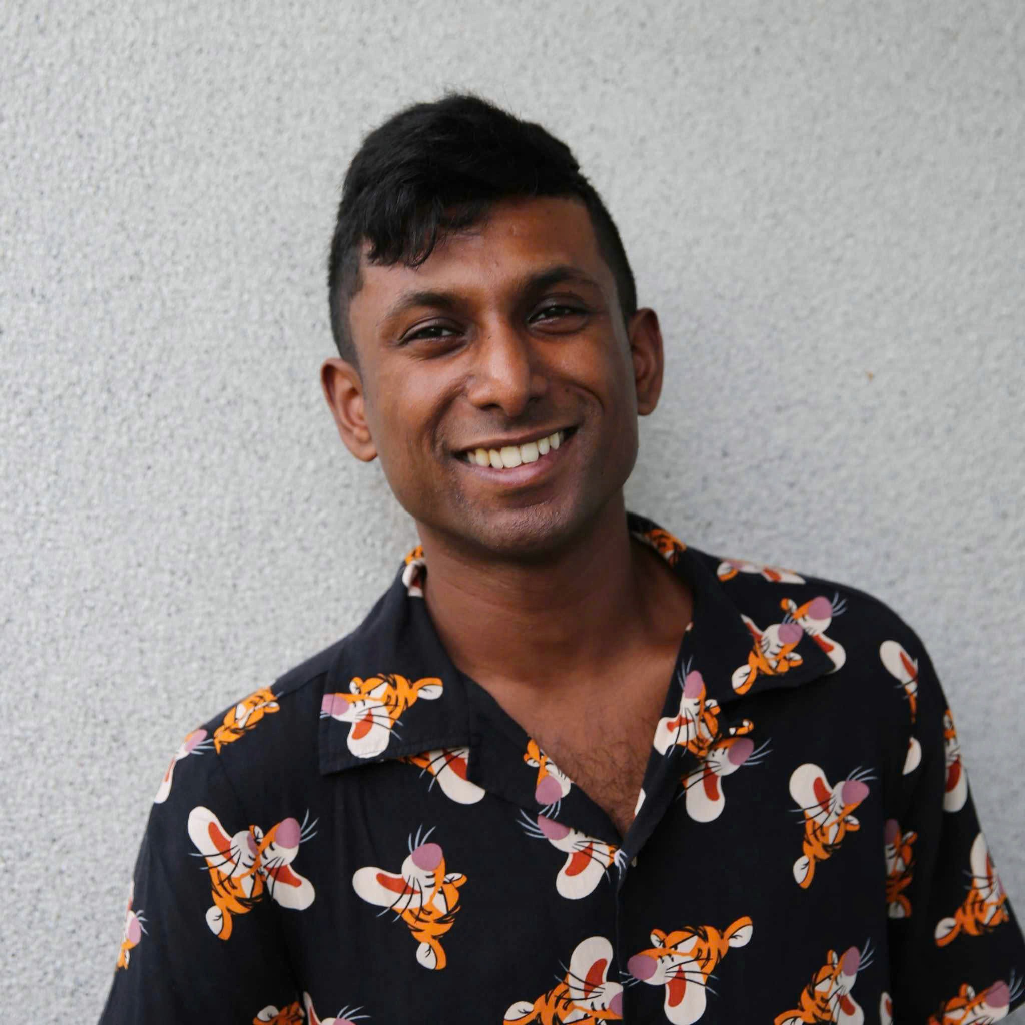 Man in apron stands in rustic kitchen, hands dusted with flour.
