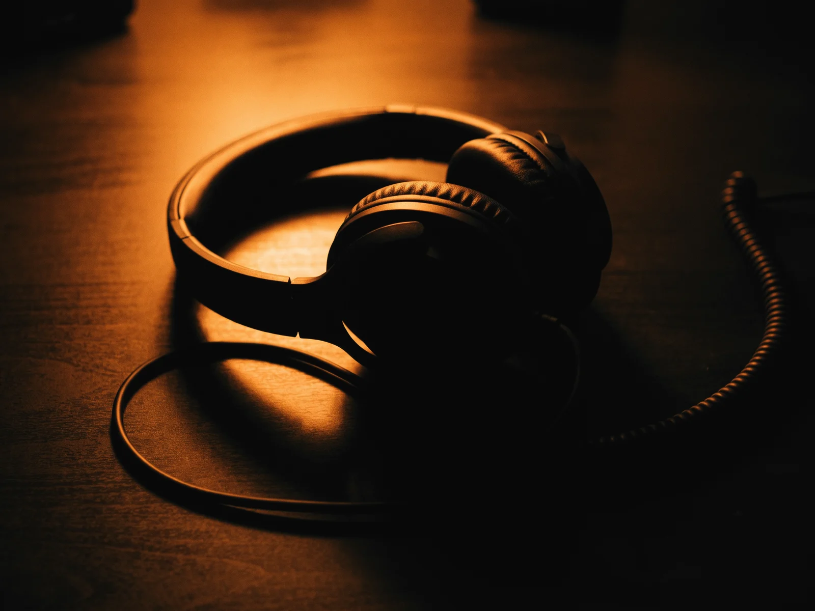 Headphones and a coiled cable on a desk in warm light