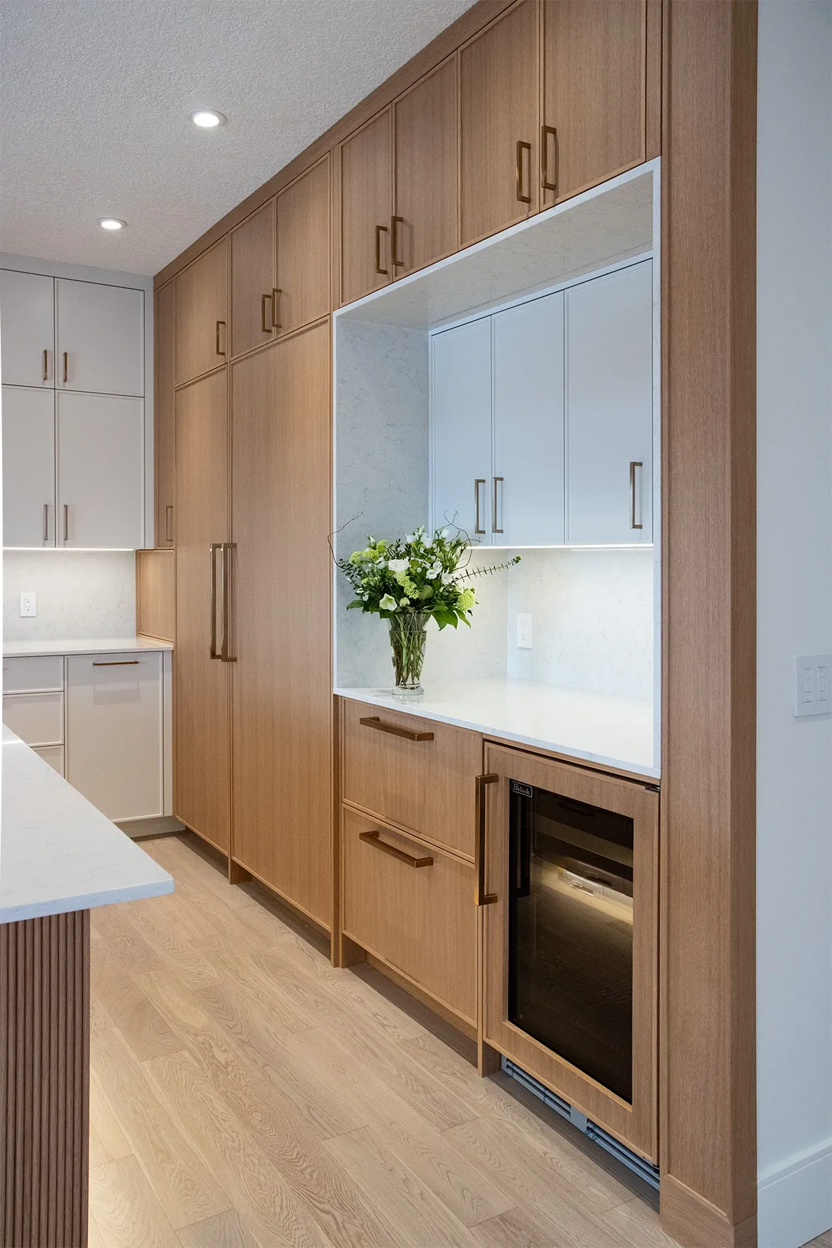 Image of modern dry bar with large slab surround and a beverage fridge and freezer drawers.