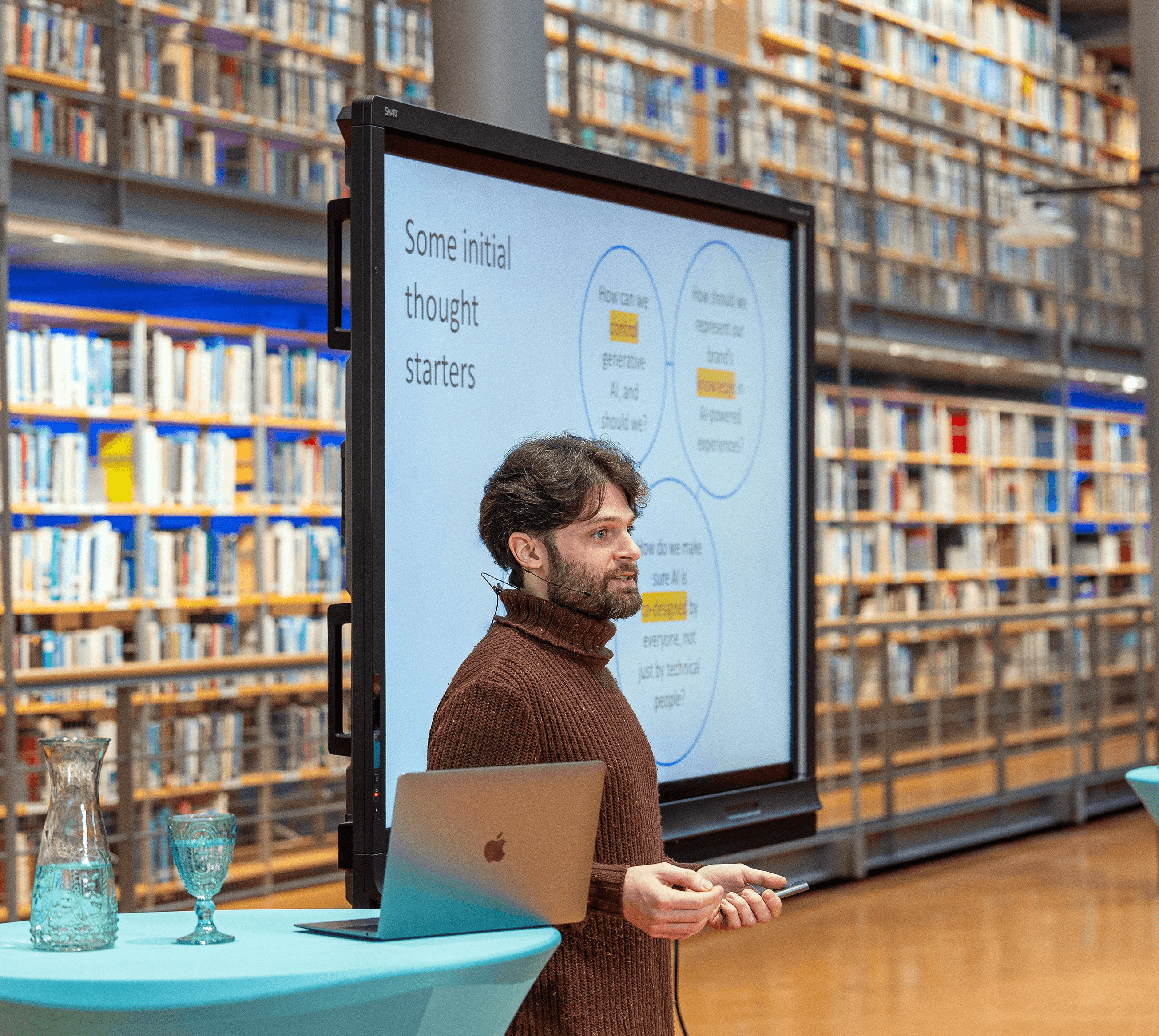 Black and white image of people working at a table with laptops, showing hands gesturing during discussion of digital content displayed on screens, with fabrica® logo in the corner.