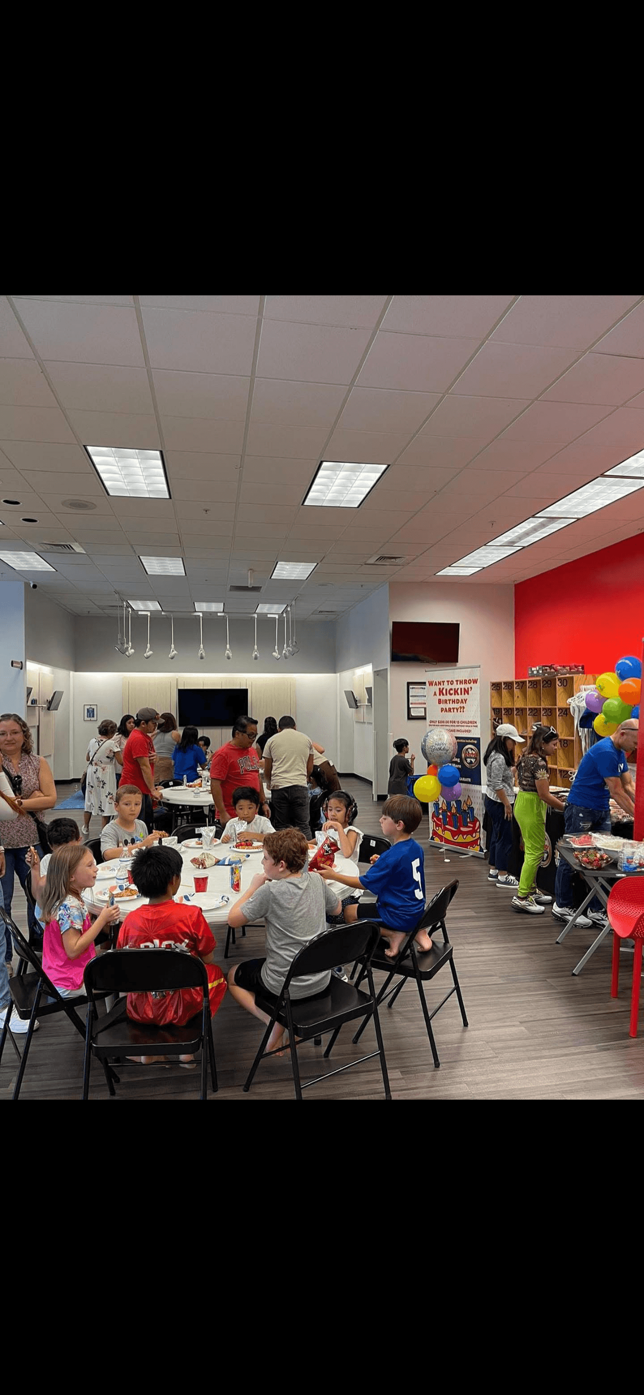 Children sitting at round table have lunch at birthday party.