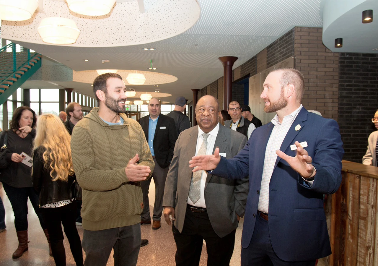 An image of 3 men talking in the entryway of a community center.
