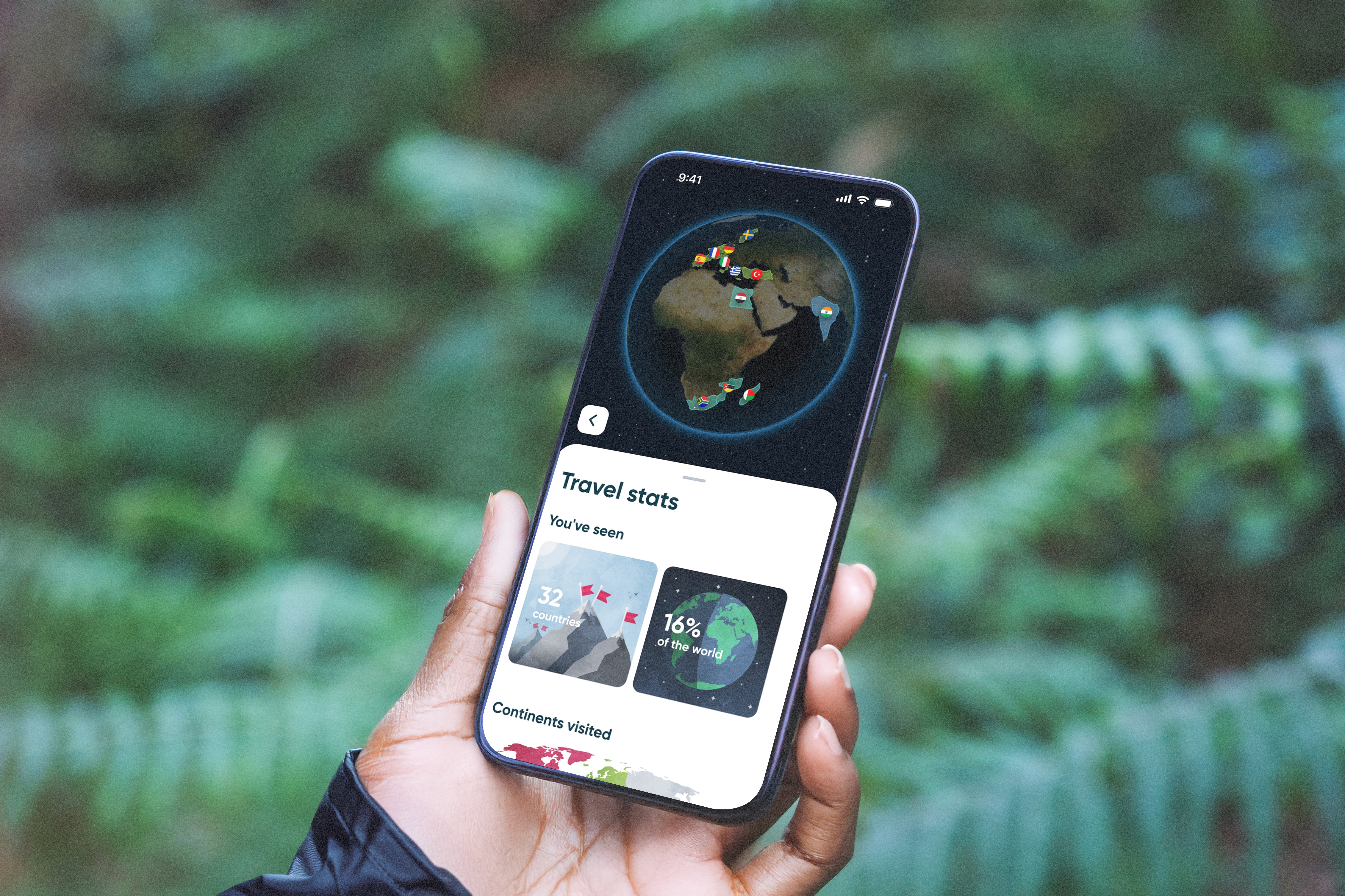 A hand holding a phone displaying Polarsteps travel stats, with a globe view and percentage of the world visited, against a forest background.