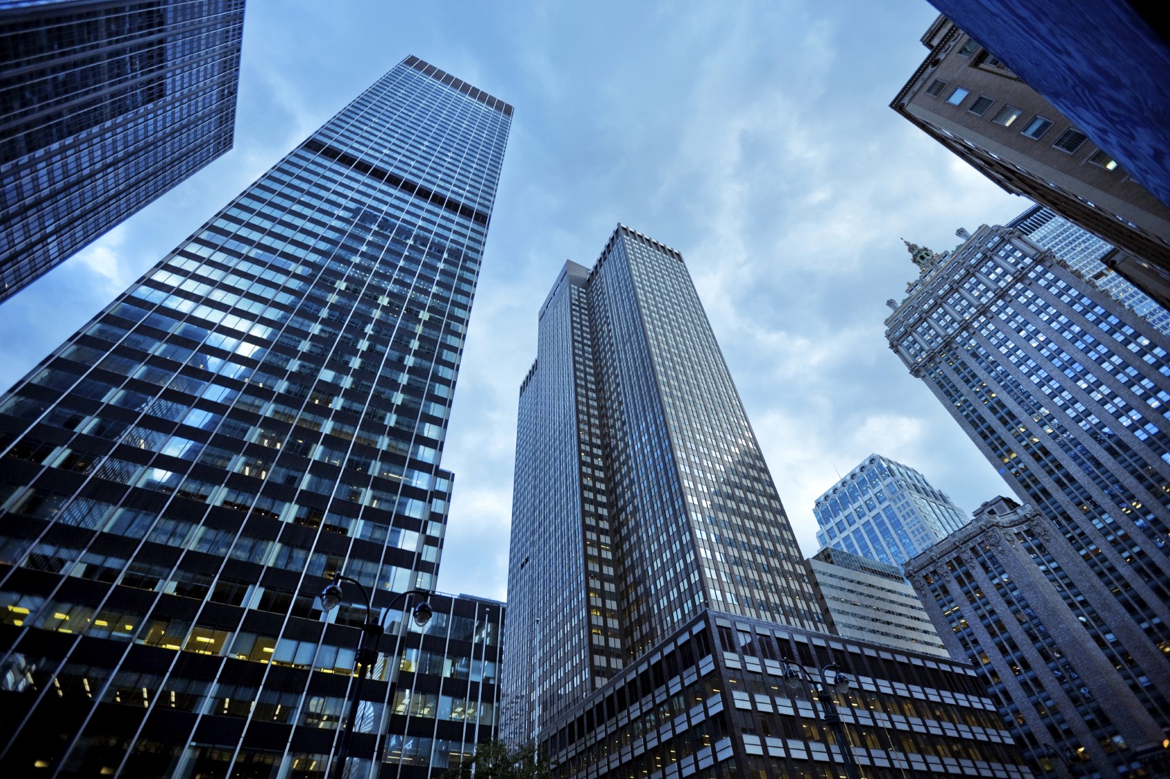 Skyscrapers looming overhead against a clear blue sky, symbolizing ambition and progress. Emphasizing the towering presence of corporate giants, a visual representation of thinking big and embracing innovation at the core of corporate culture