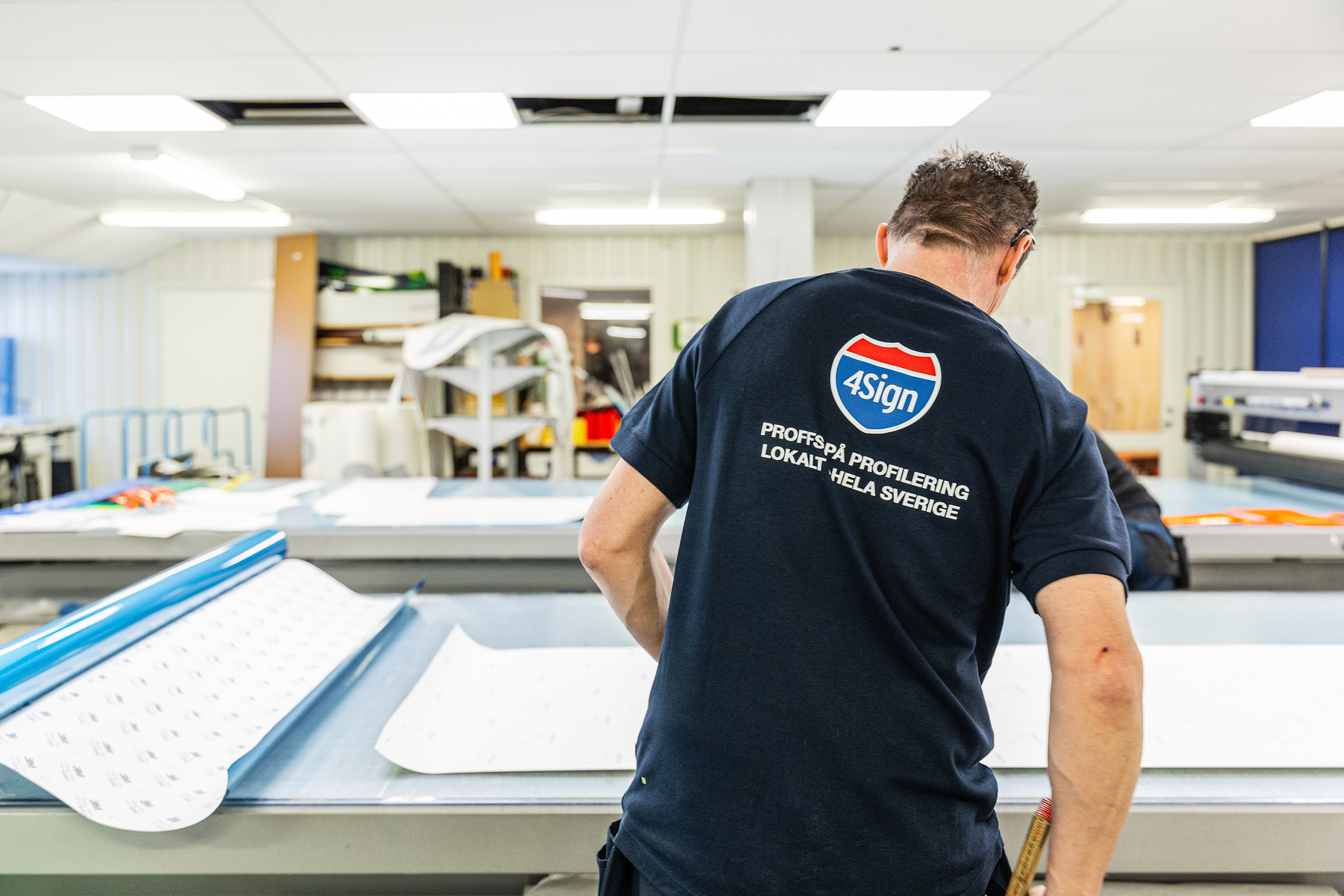 Kund granskar arbetskläder och varselkläder i 4Signs butik, brett utbud av profilprodukter.