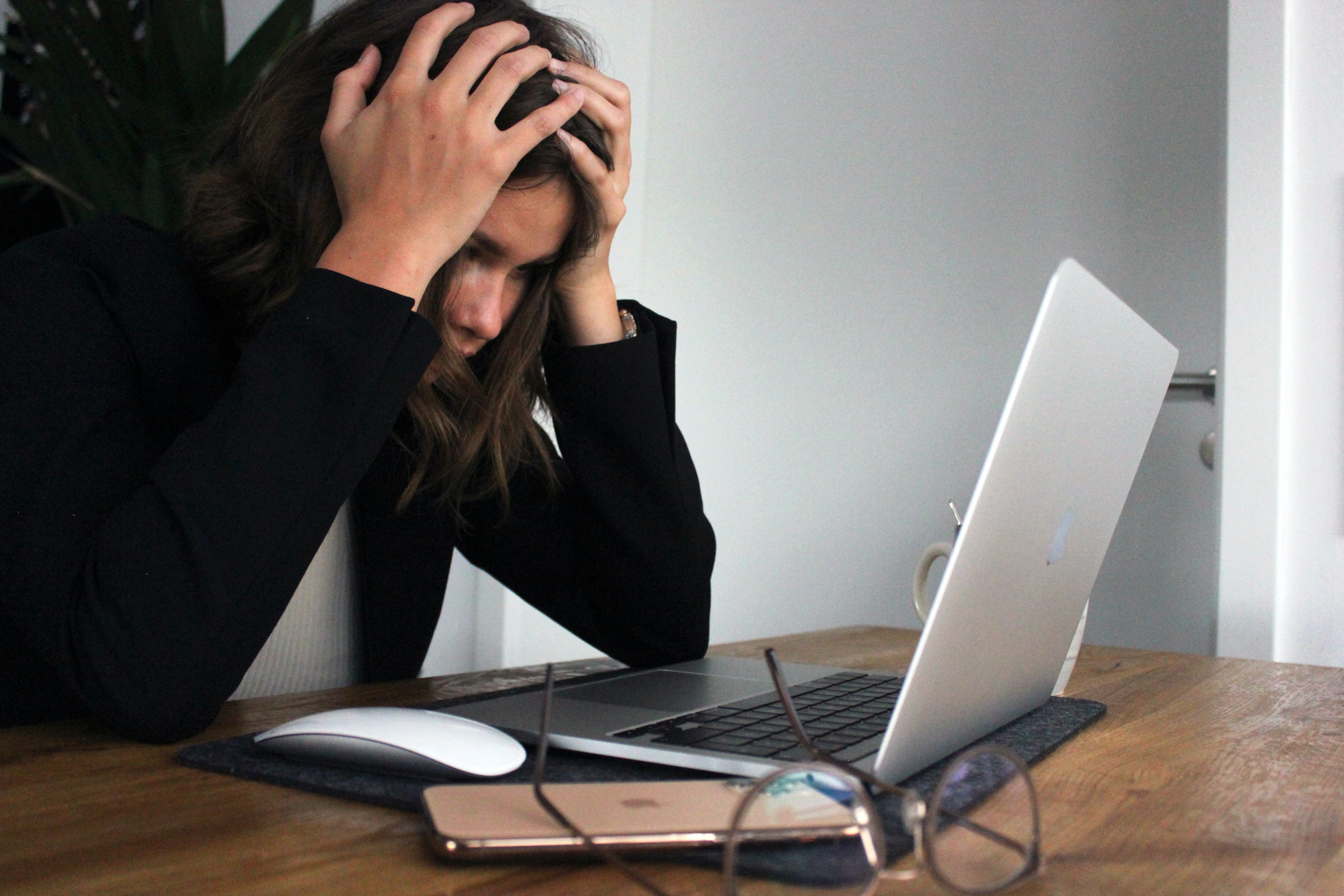 A woman holding her head with and looking anxious, and concerned while using her laptop and getting to know about the risks of not setting up email authentication