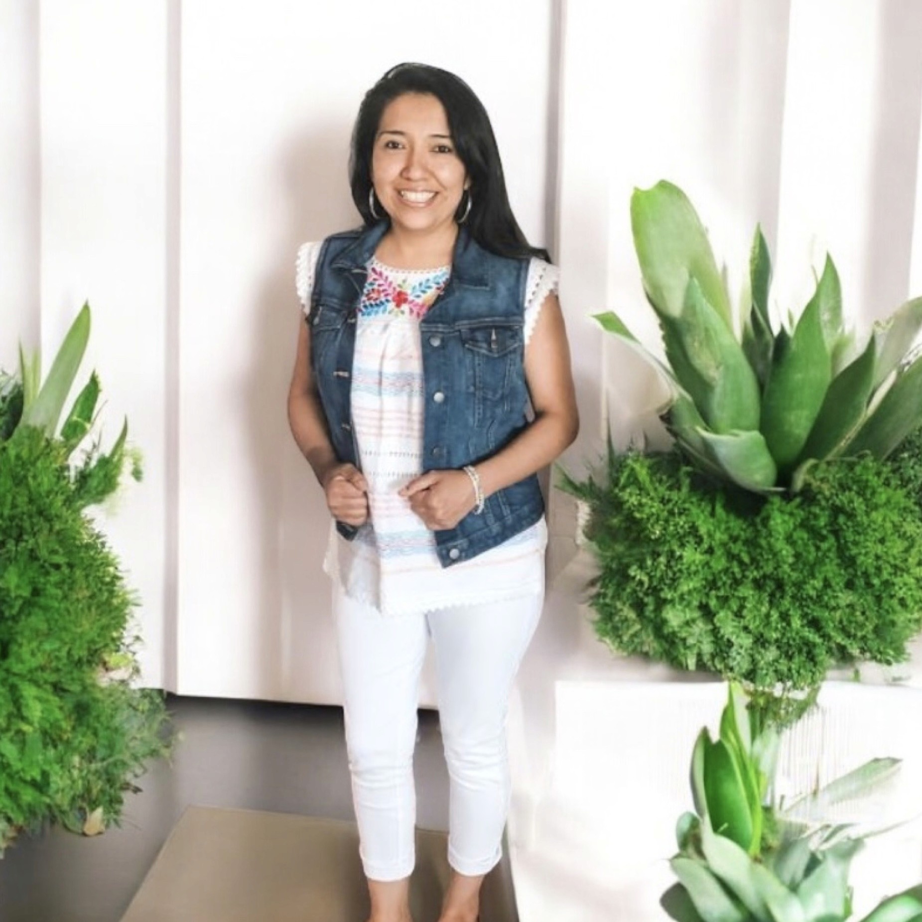 Owner of Susa’s Sweets & Balloons smiling, standing next to decorative plants