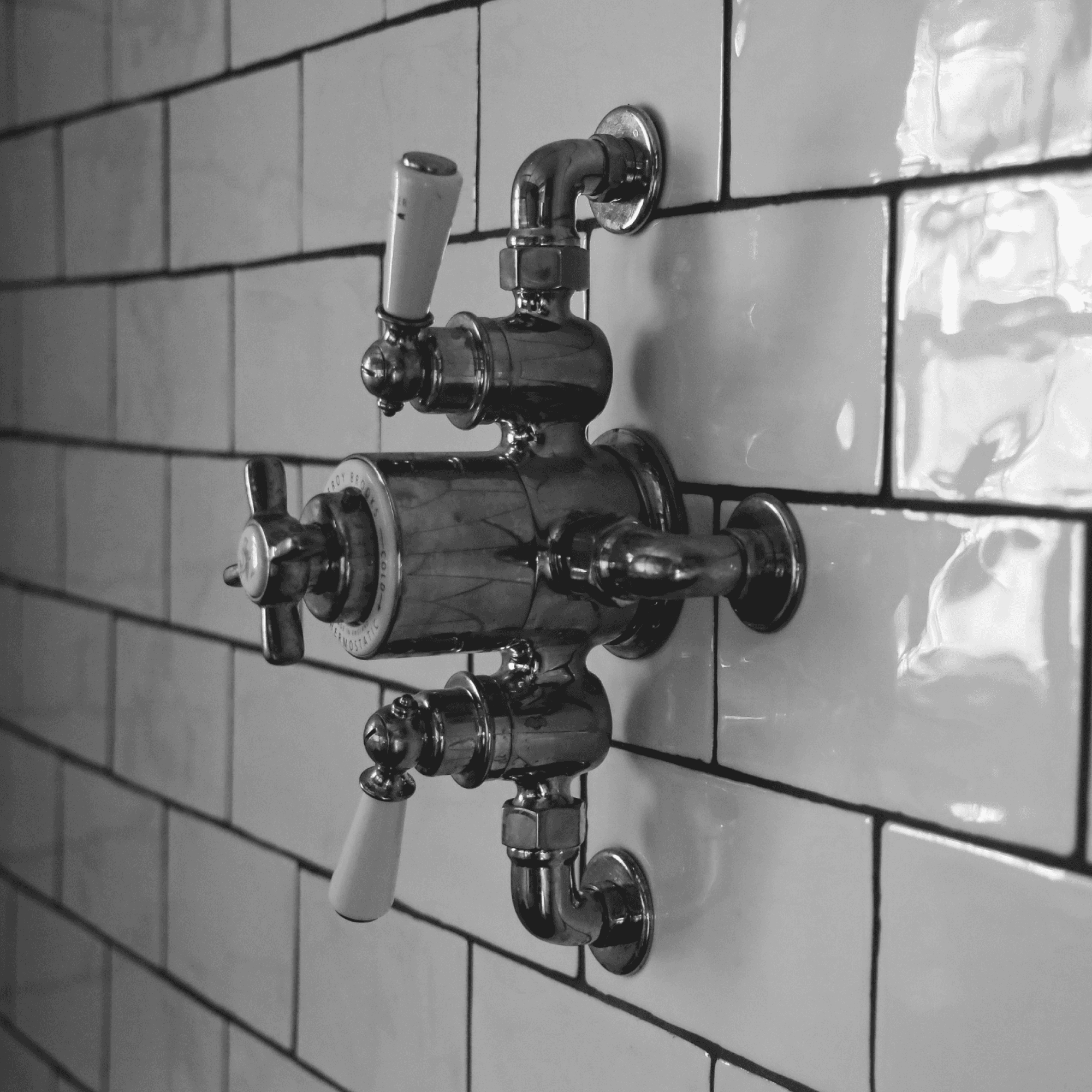 Shower mixer controls on white metro tiled wall