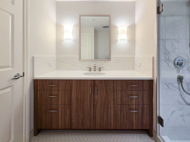 Image of Modern primary ensuite bathroom design with marble accents and wooden cabinetry by KHD Homes.