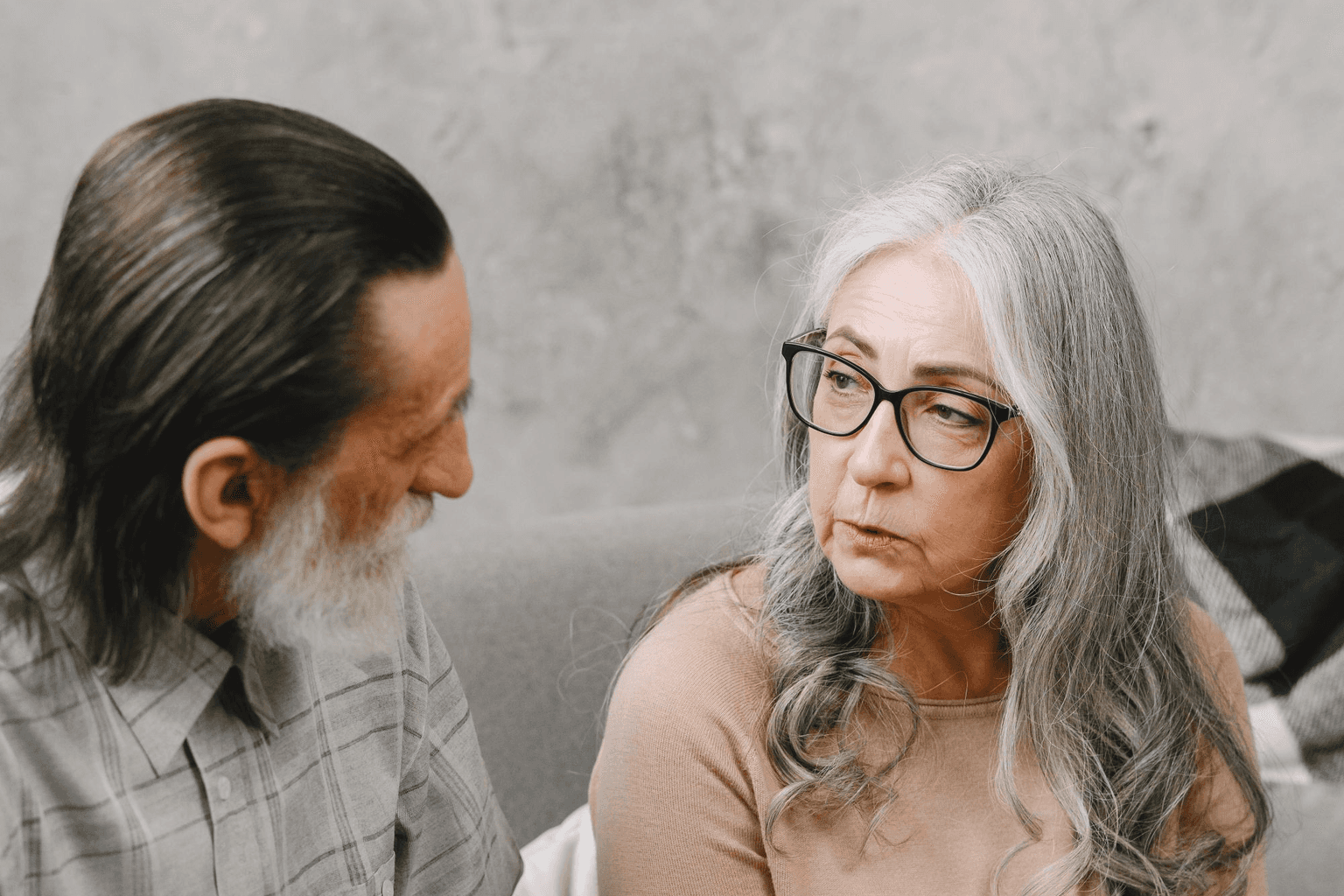 An older couple sitting close in conversation, talking something difficult through.
