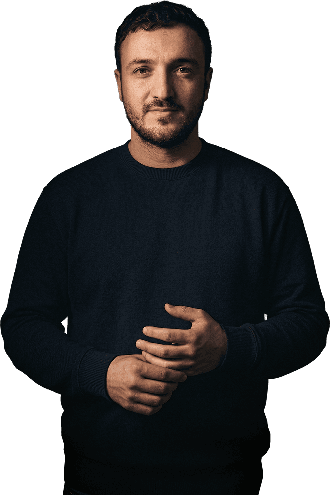 Portrait of a man with dark hair and a beard wearing a dark blue sweater