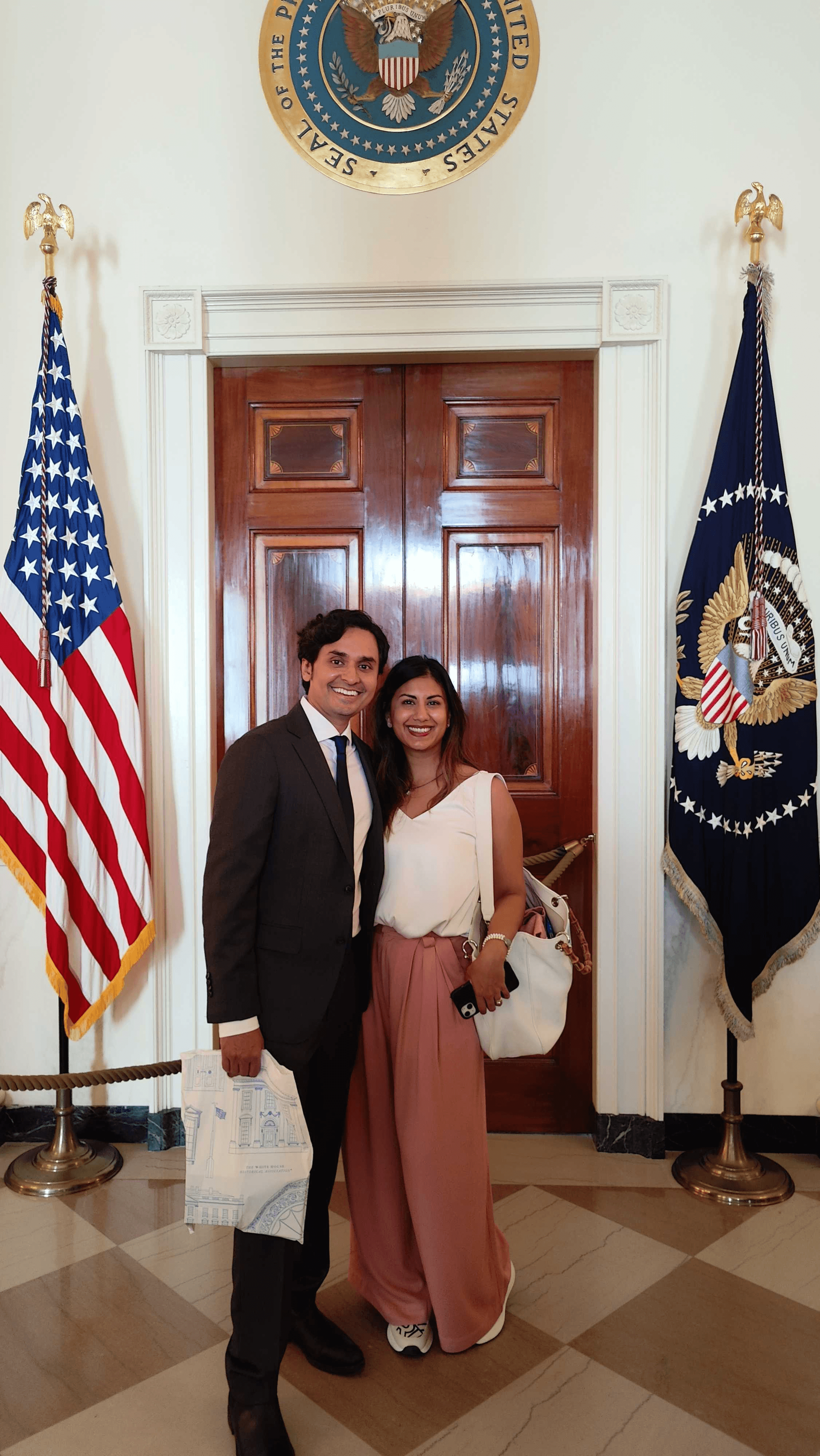 A man and woman pose in front of a presidential seal