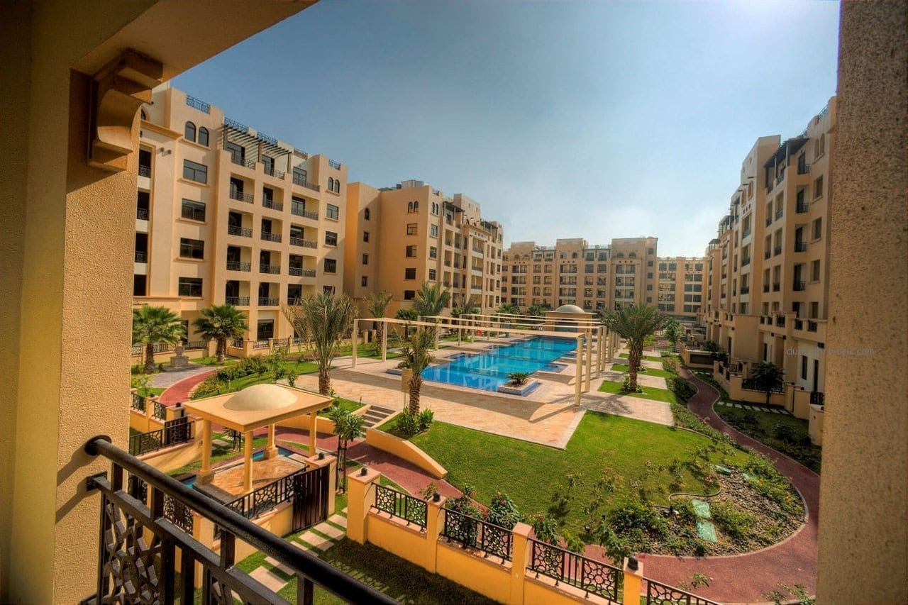 A park featuring a fountain and playground, located in a residential area, titled The Square by OMNIYAT.