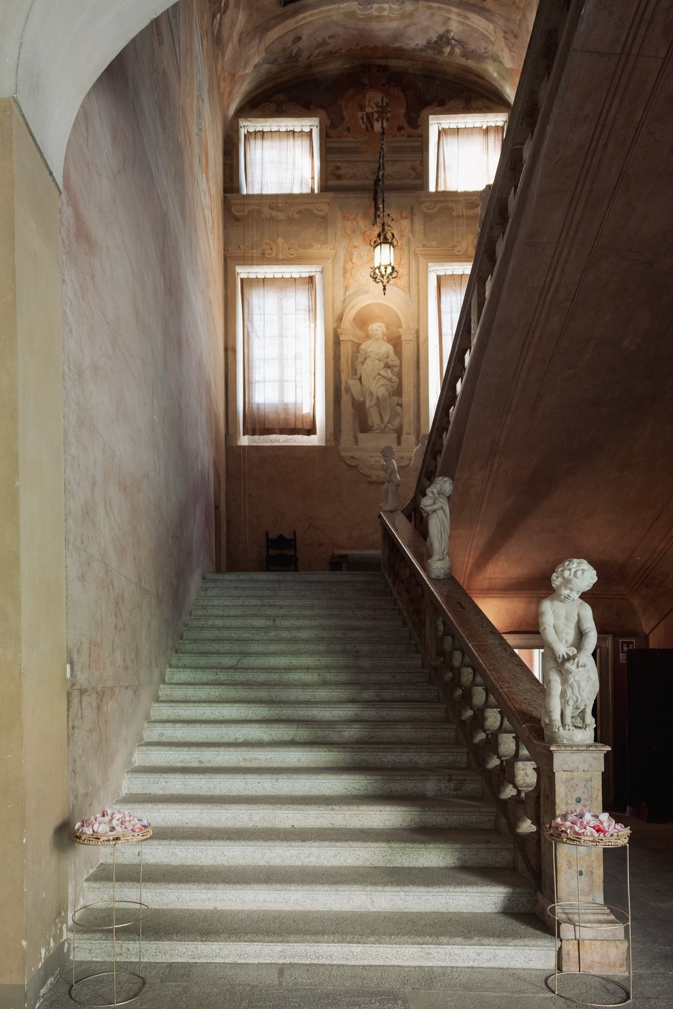 Scalone della Rocca di Soragna con fiori alle balaustre, luce dalle finestre, atmosfera solenne per il matrimonio