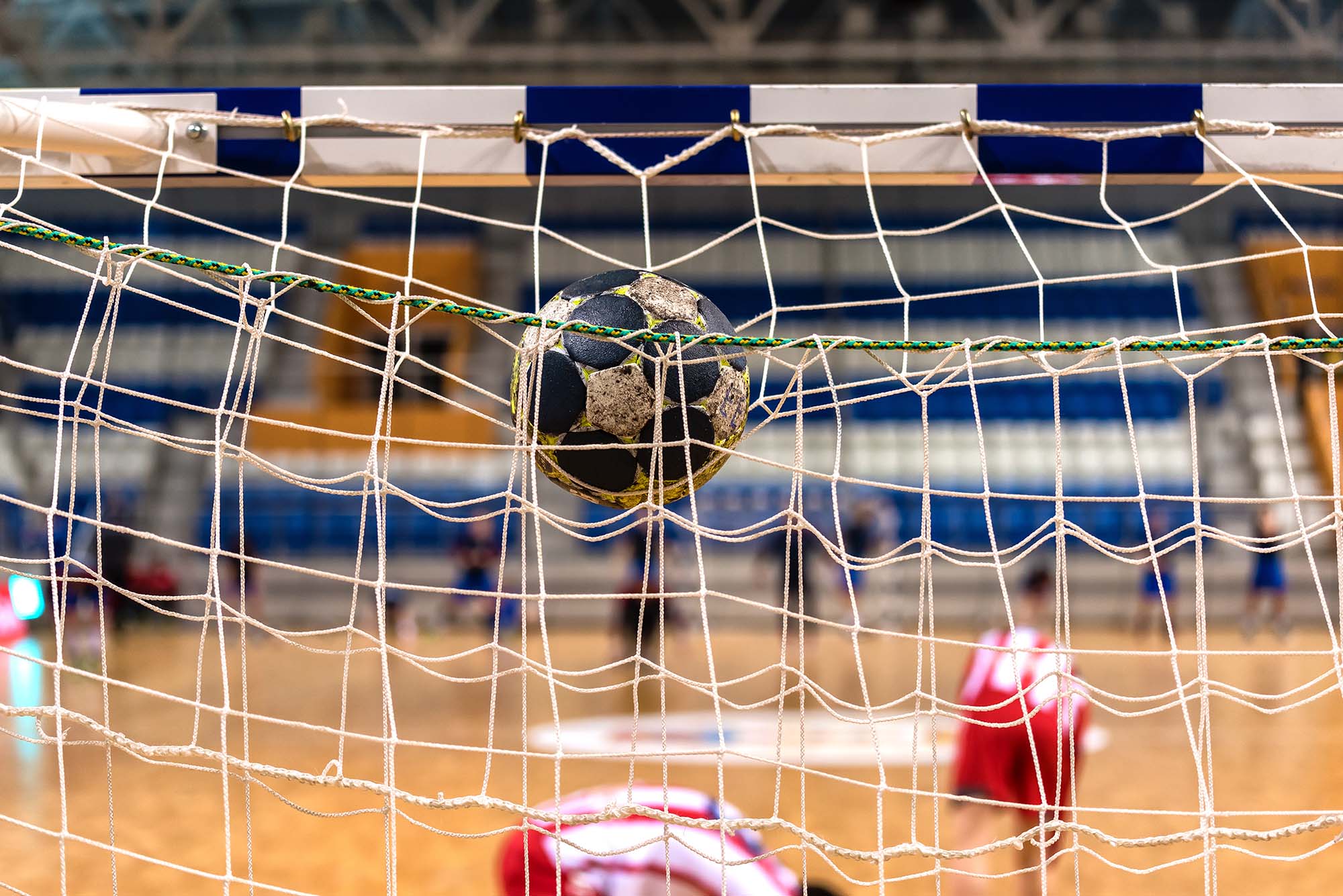 A worn handball lodged in the back of the net after scoring a goal during an indoor match.