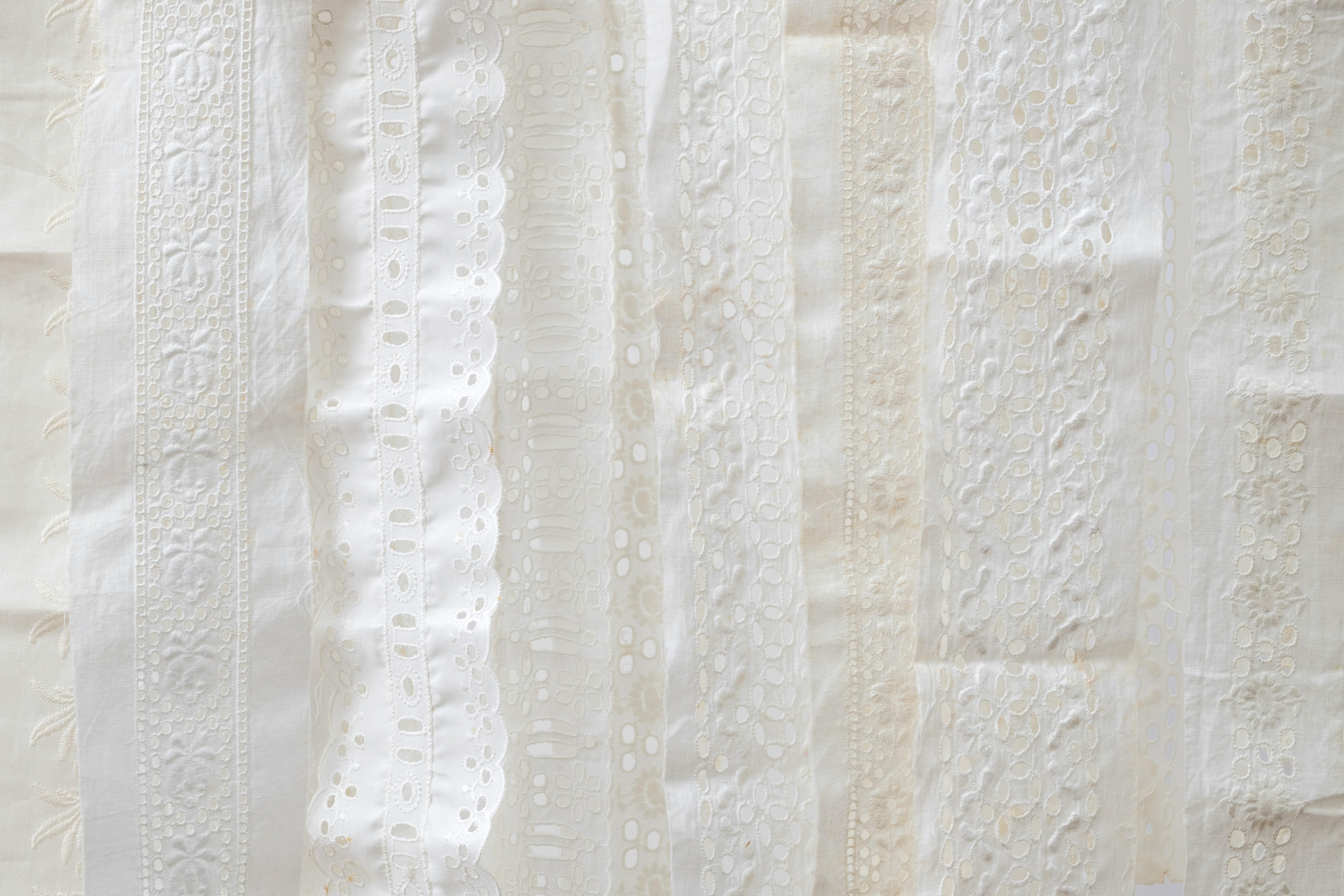 Restaurant interior with wooden tables and chairs lined against a textured wall, softly lit by round wall lamps.