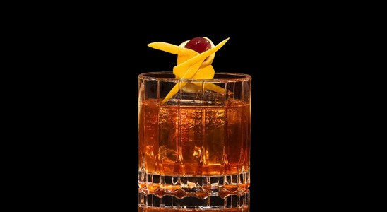 A closeup of a Prohibition Old Fashioned drink against a dark background.