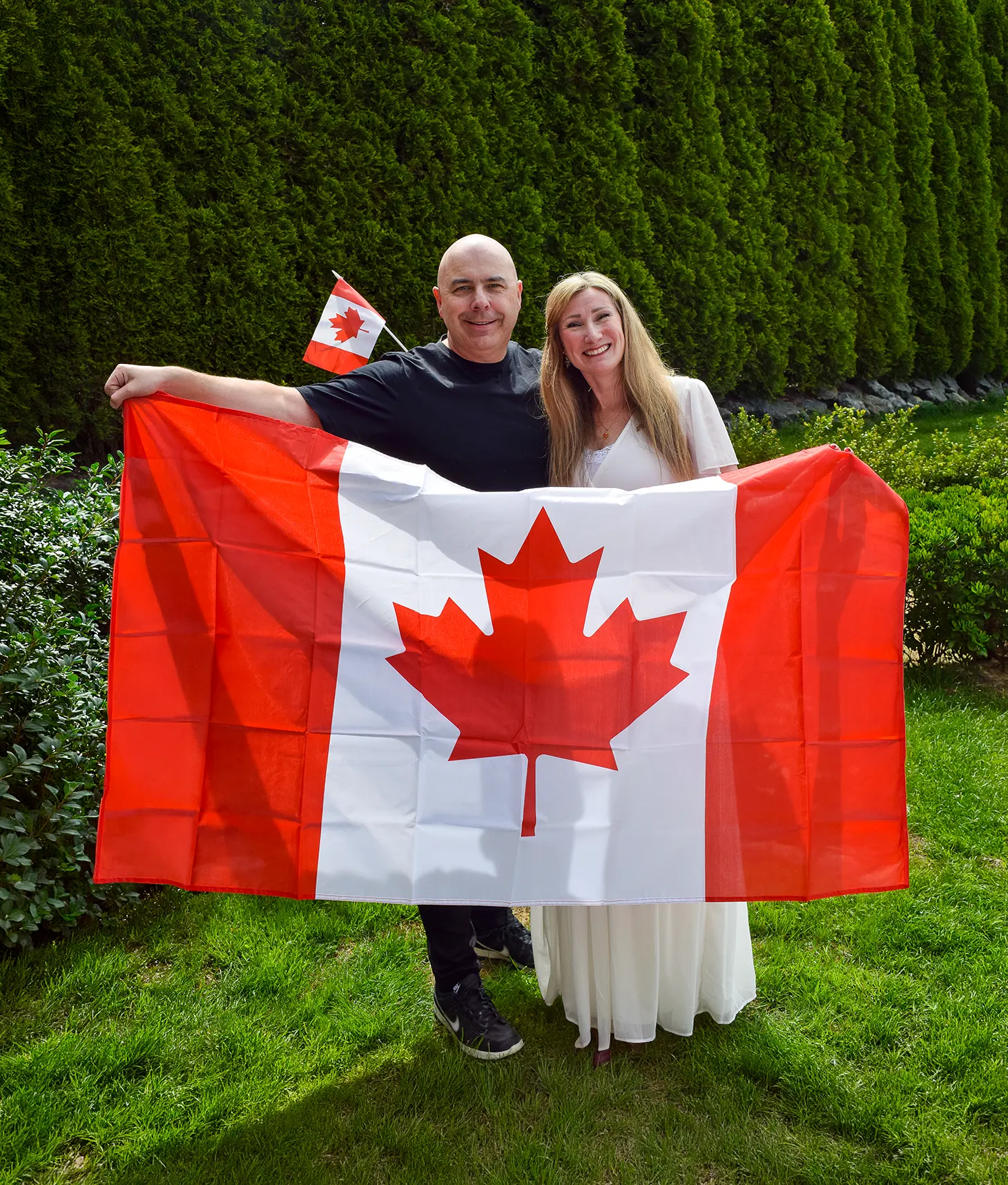 Image of Runar and Cecilia Pedersen holding up the Canadian flag outdoors.