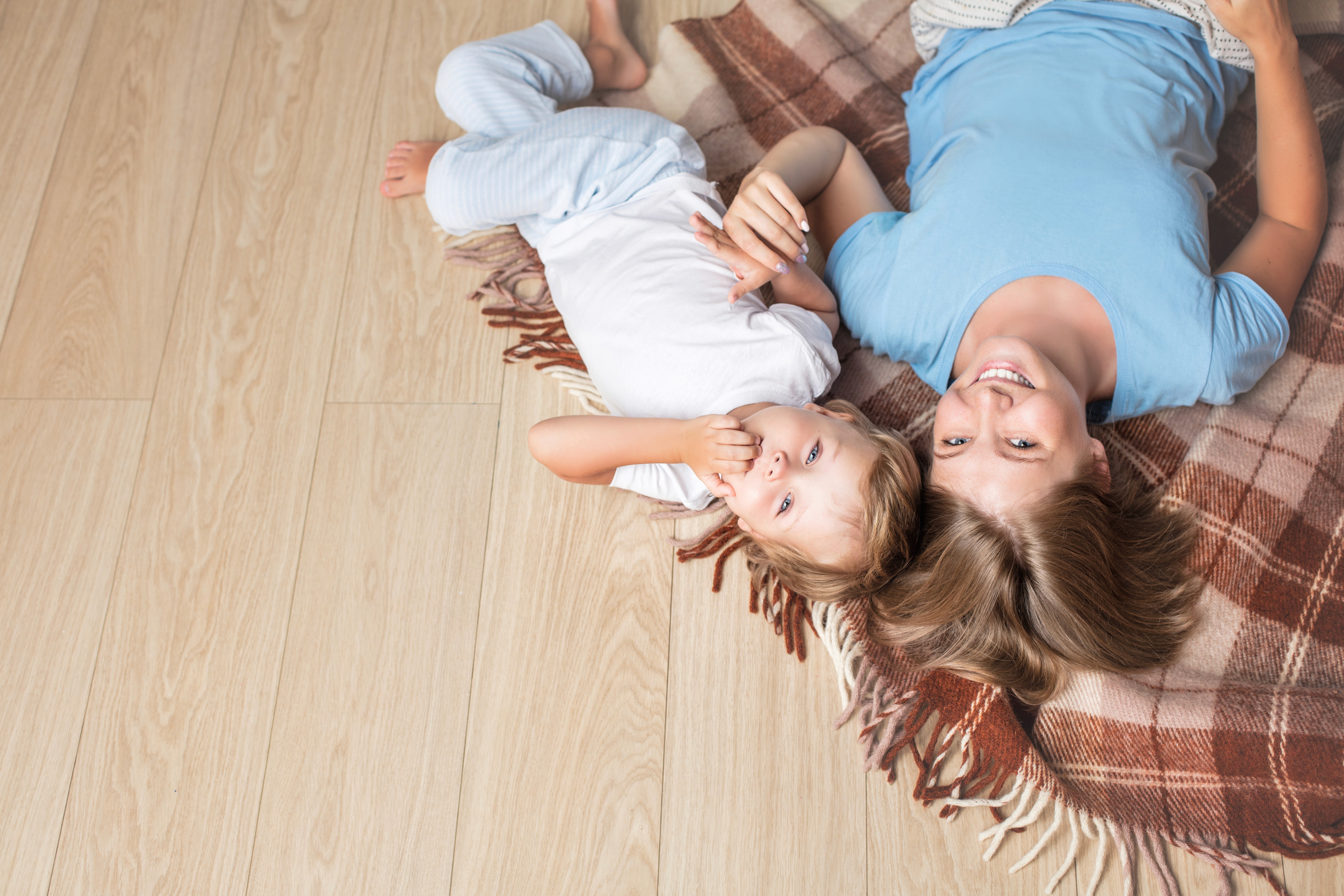 Mother and child relaxing on warm timber-look flooring, enjoying a safe, comfortable surface made for everyday family life.