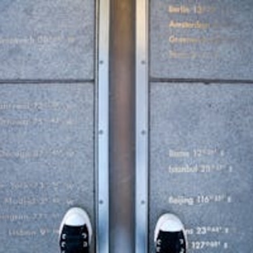 Un paio di sneakers appoggiate su una superficie di cemento con del testo inciso e una linea metallica che divide due metà.