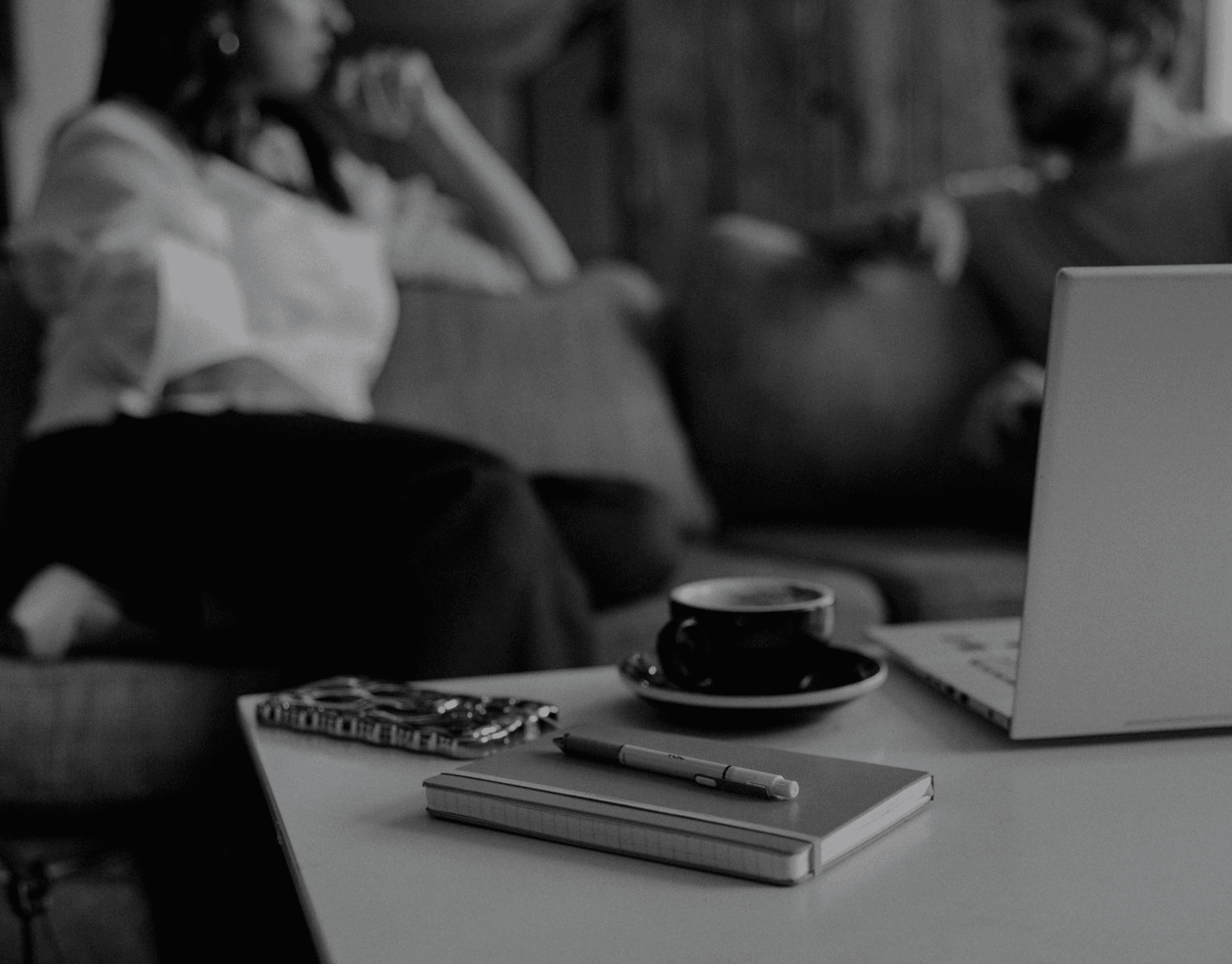 Stacy and another person seating on a sofa and talking in front of a laptop and a cup of coffee
