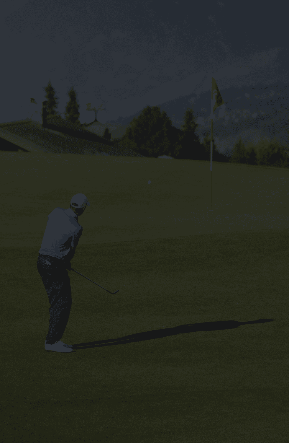 Generic faded background image of a golfer chipping to a red flag and mountains in the background
