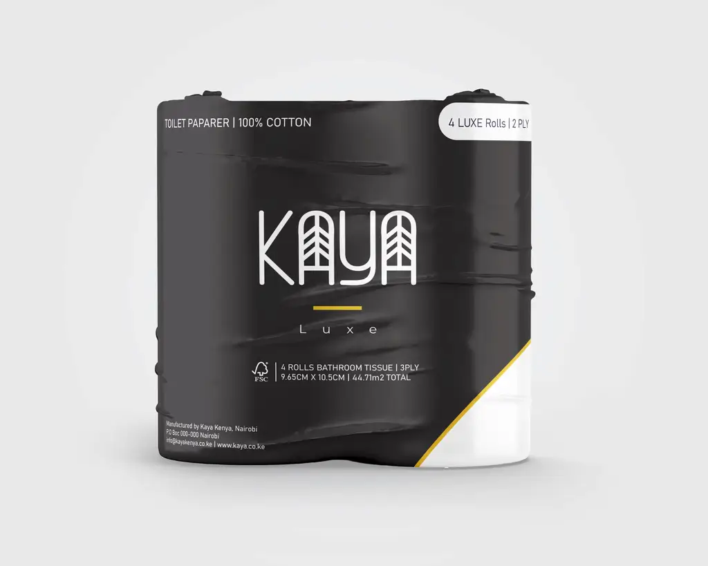 A person in a white outfit sits on a round stool in a spacious, minimalist room. The wall is covered with framed photos surrounding a large screen, creating a serene, contemplative atmosphere