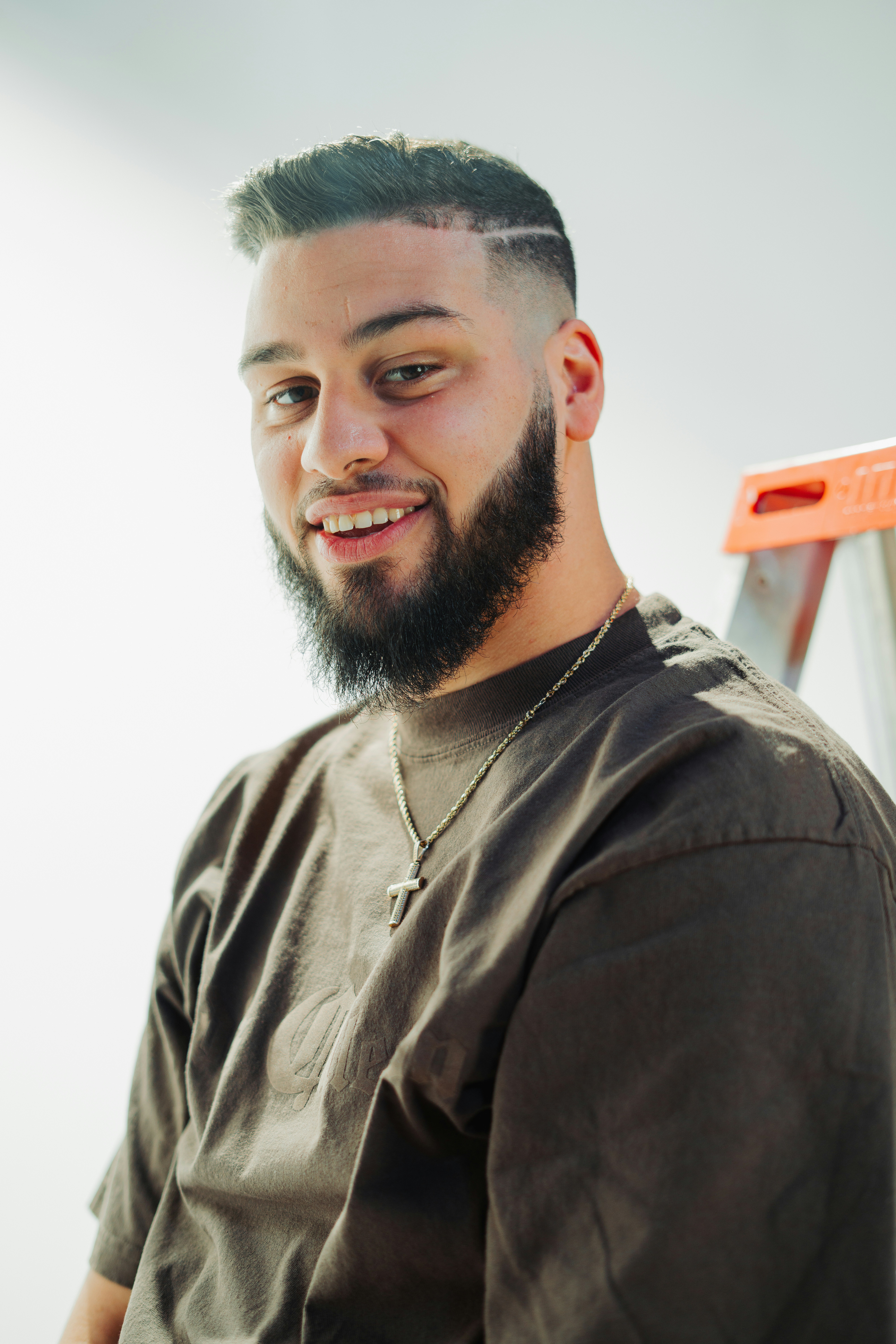 a man with a beard standing in front of a ladder