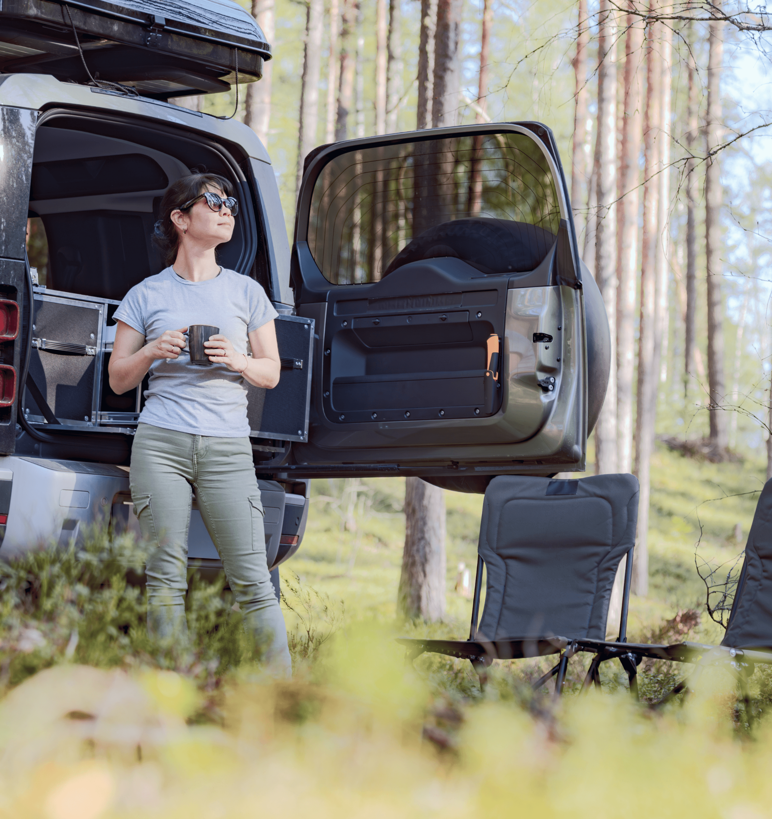 Woman near van lookin at the sky in the woods
