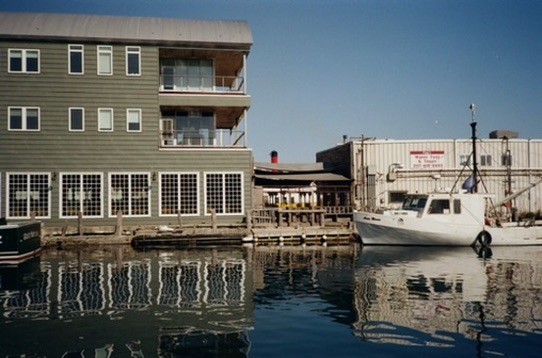 Wooden waterfront buildings reflected in calm harbor water