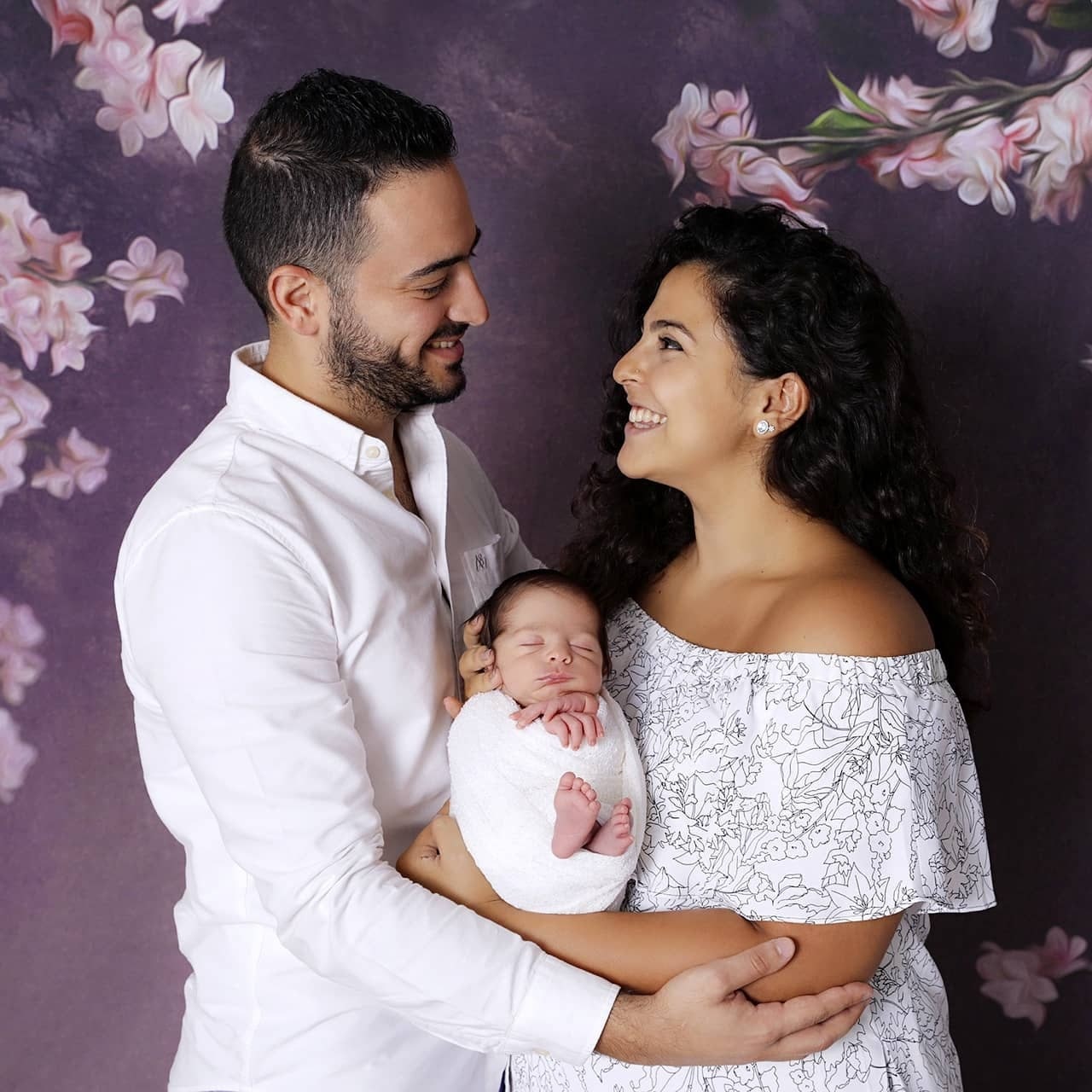 Happy couple with newborn in clean white space, ideal for couple photoshoot with family focus.