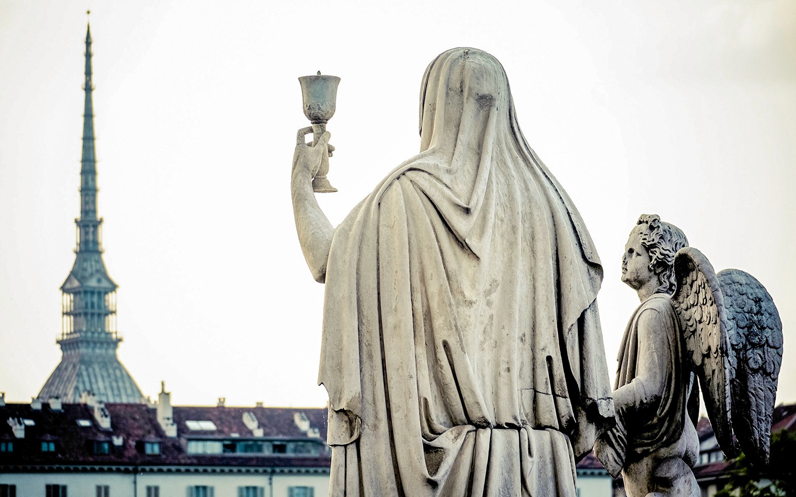 Statue som holder en kalk med en engel foran Mole Antonelliana, Torino Magica-tur.