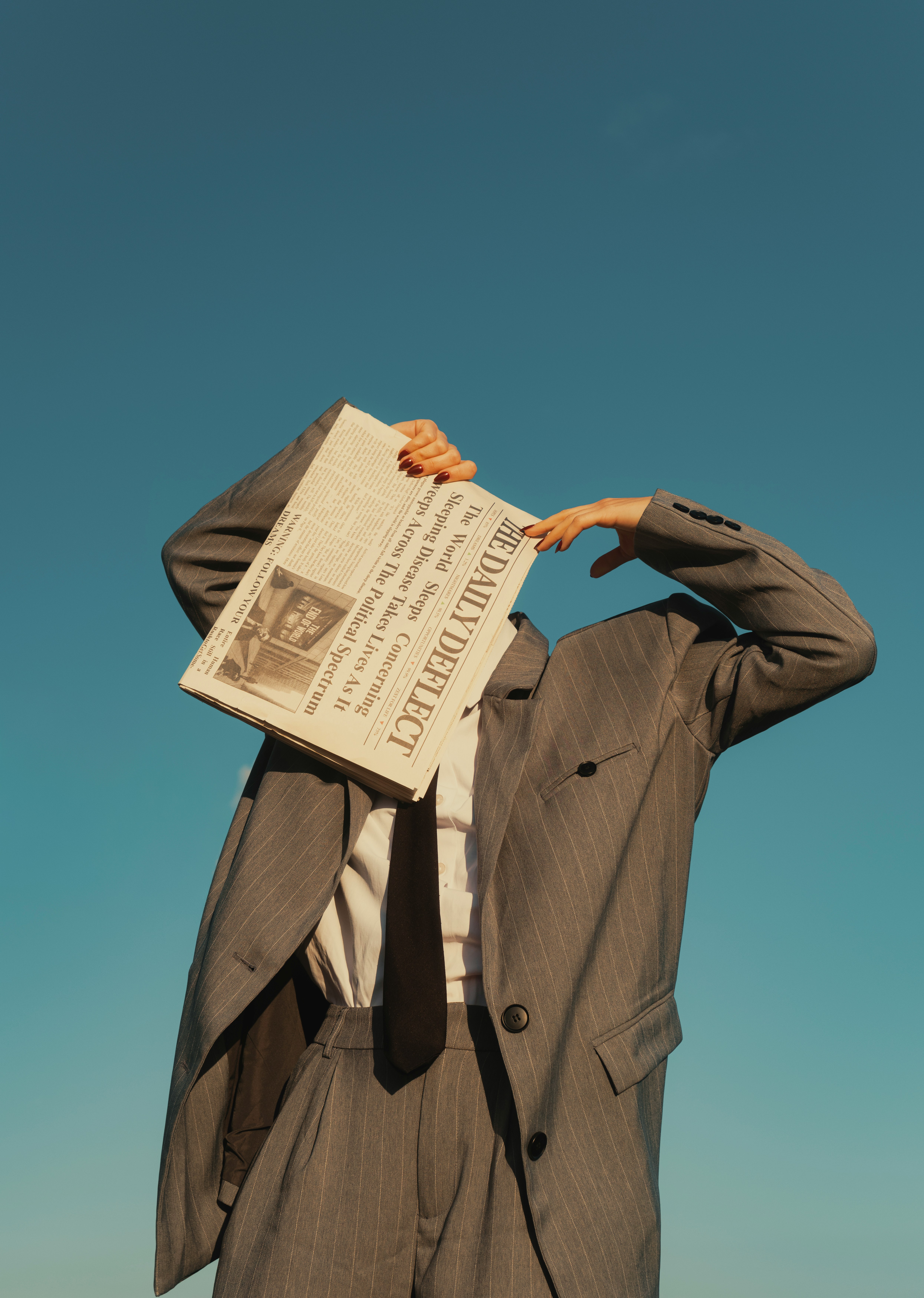 Person in suit holding newspaper over face