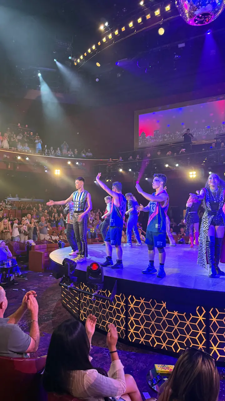 Performers standing on stage at the end of the Mad Apple show in Las Vegas, waving to the audience.