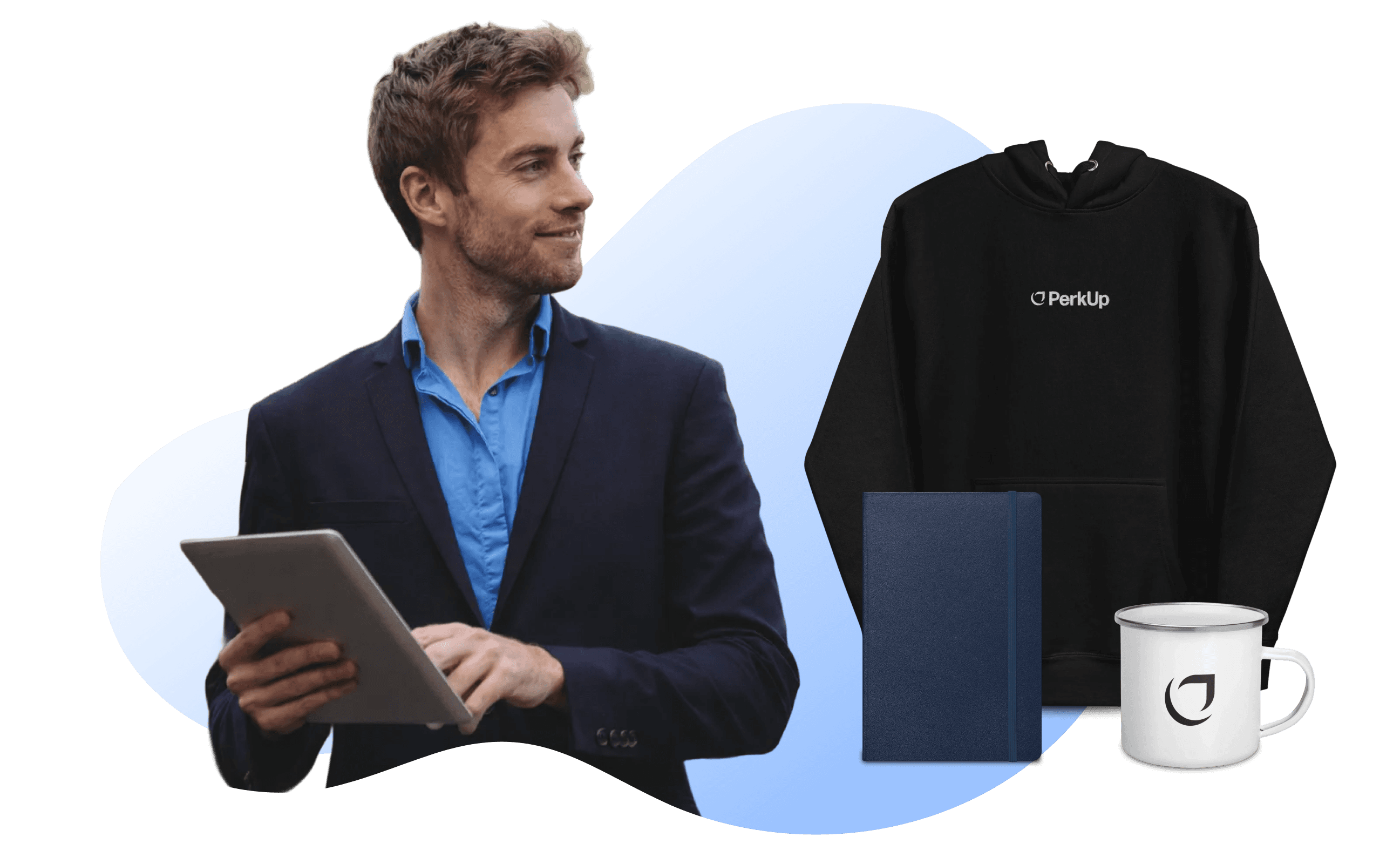 A man holding a tablet. Beside him are a notbeook, a mug, and a hoodie.