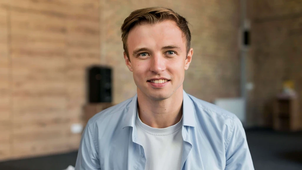 a man in a blue shirt smiling at the camera