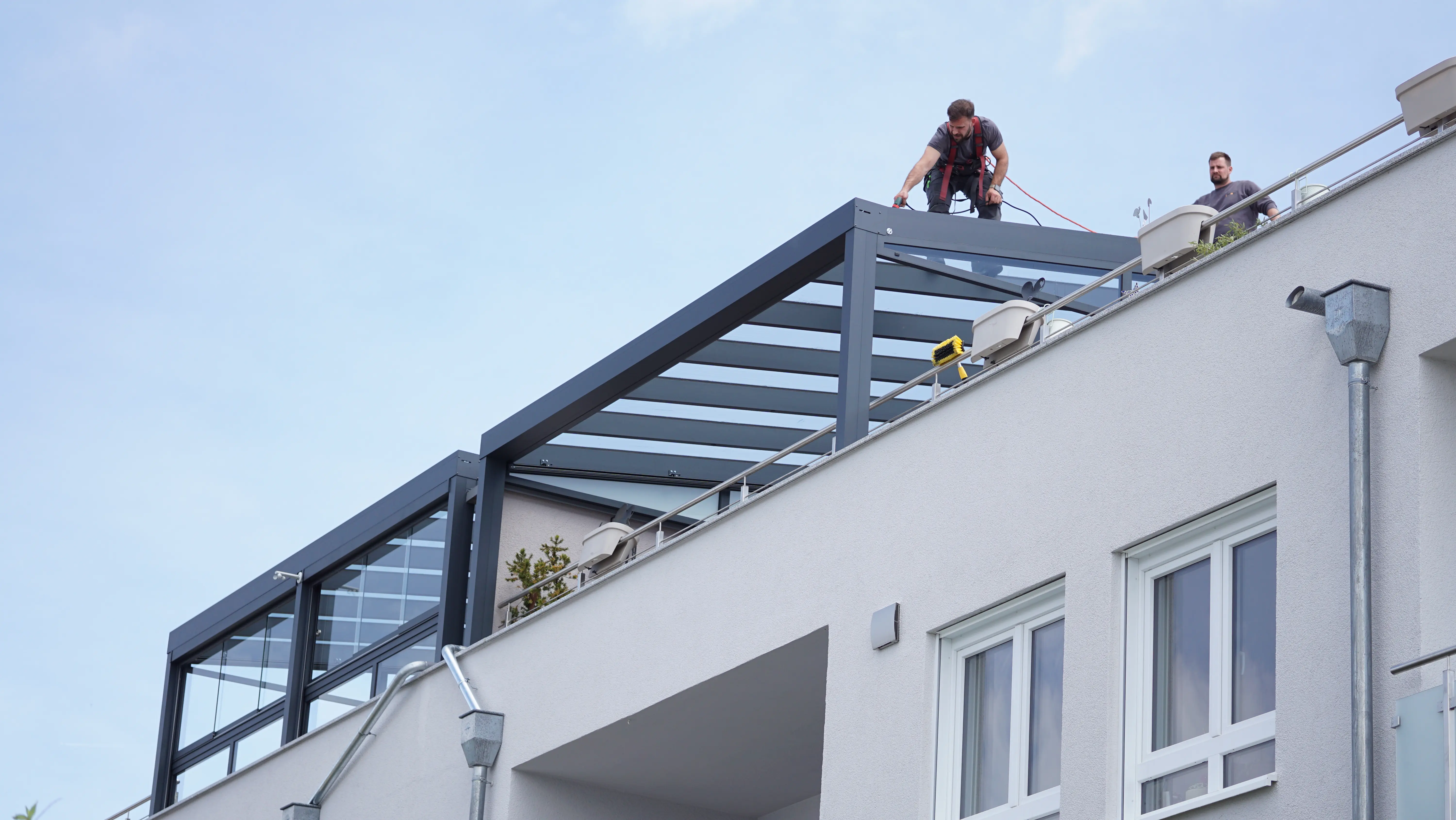 Harmes-Monteure montieren eine Terrassenüberdachung auf einer Dachterrasse