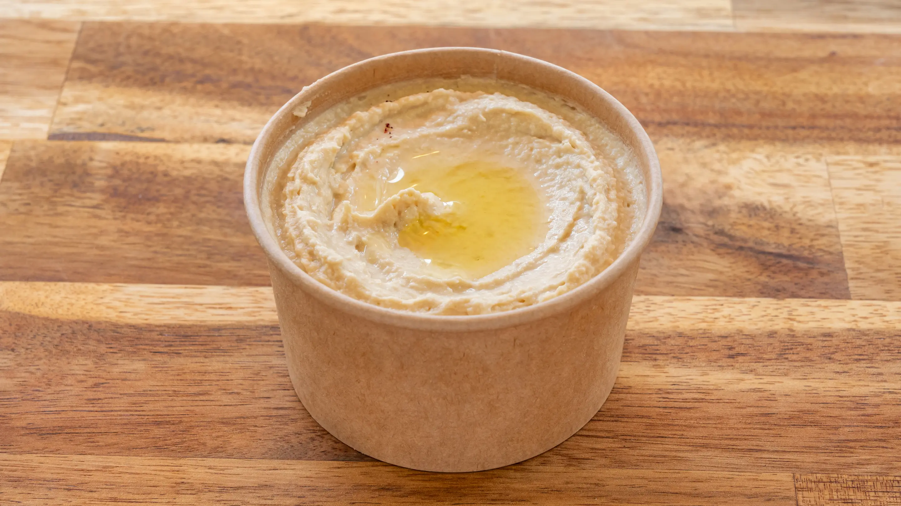 Pot kraft de houmous garni d’un filet d’huile d’olive