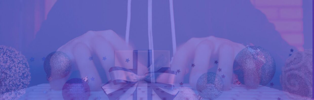 A blurred image of a person typing on a keyboard, with colorful holiday ornaments and a gift box placed around the keyboard. The background features a festive blue hue, suggesting a holiday shopping theme. Beware Holiday Shopping.